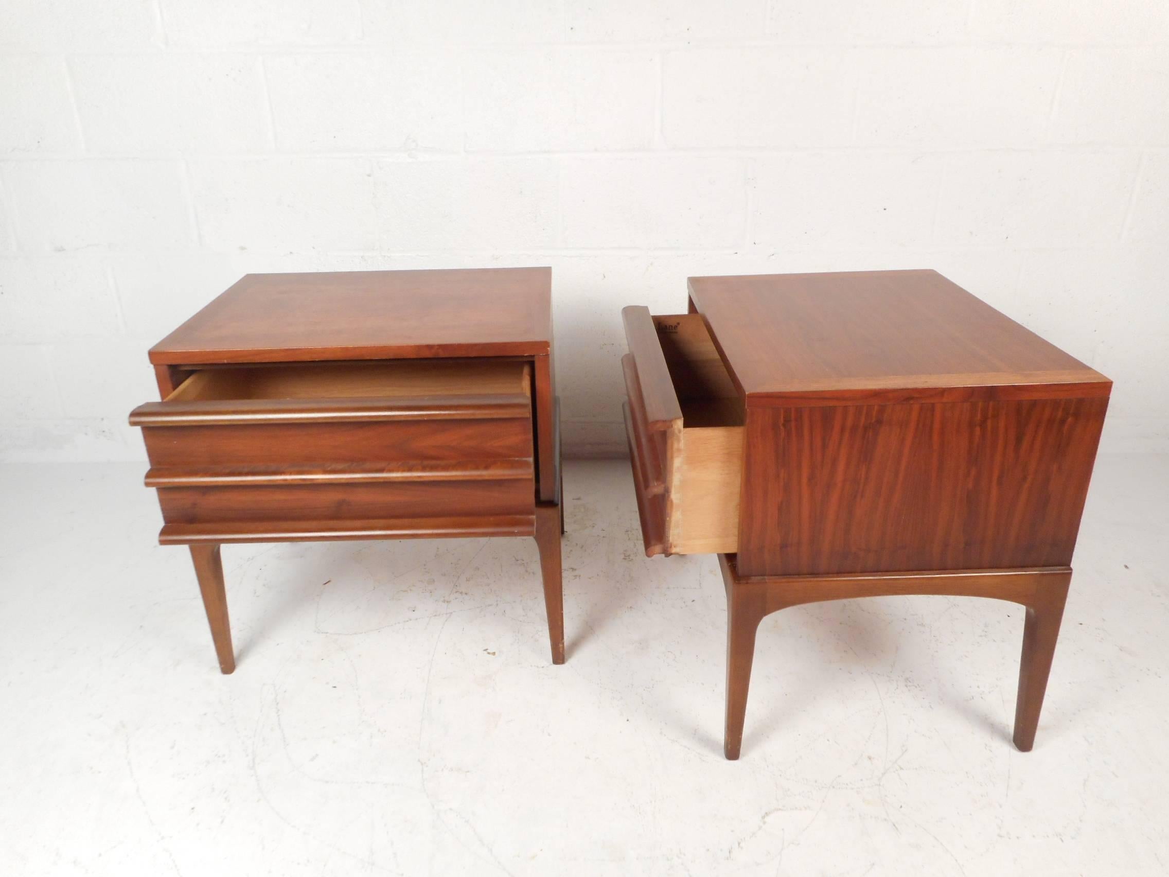 This beautiful pair of vintage modern end tables feature one large drawer with unique sculpted pulls. Quality craftsmanship on display with long tapered legs and stunning walnut wood grain throughout. This versatile pair work perfectly in the