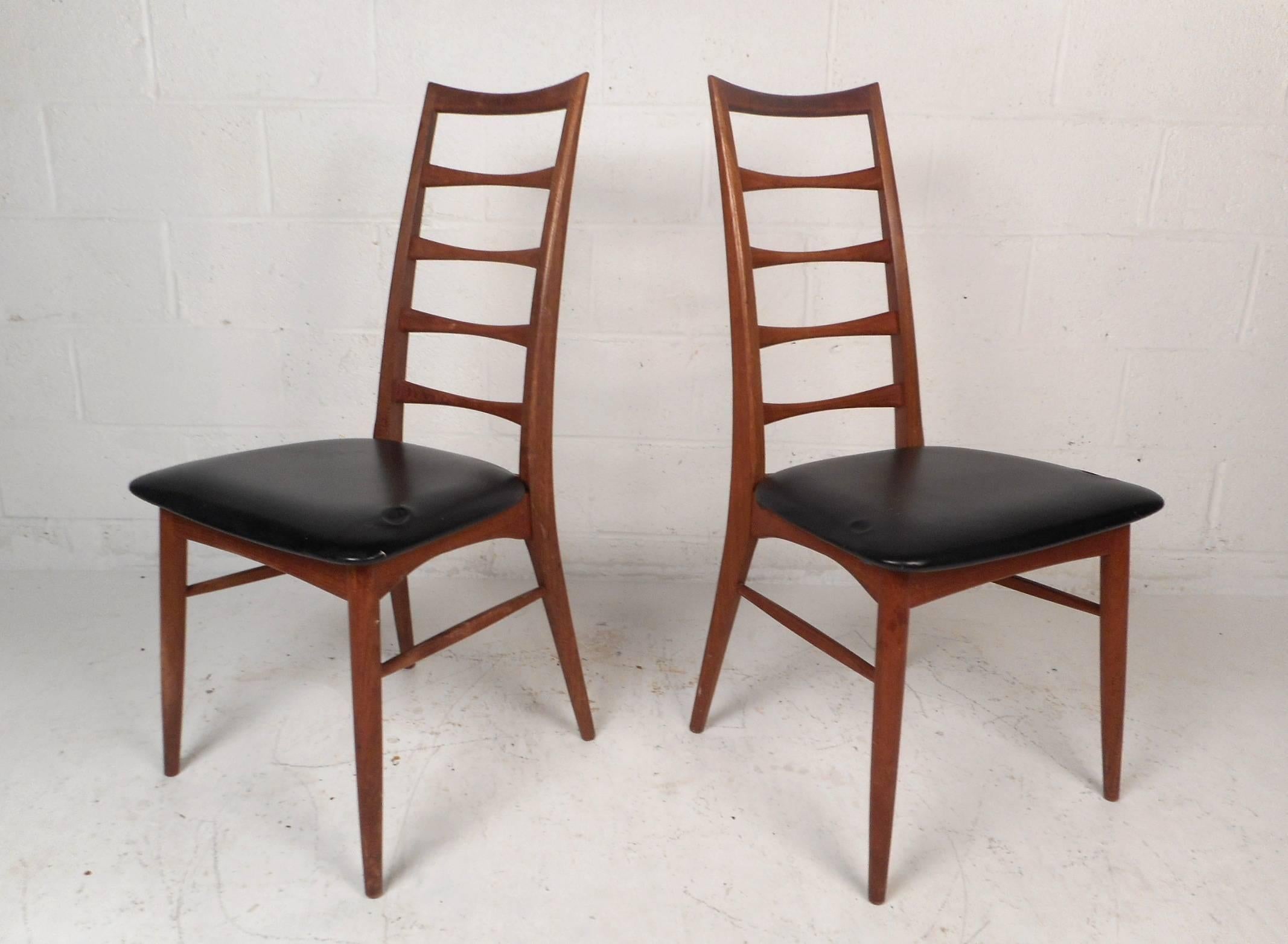 This gorgeous vintage modern pair of side chairs feature a sculpted teak frame and black vinyl upholstery. The sleek ladder backrest and angled back legs add to the midcentury appeal. Quality craftsmanship with stunning teak wood grain ensures