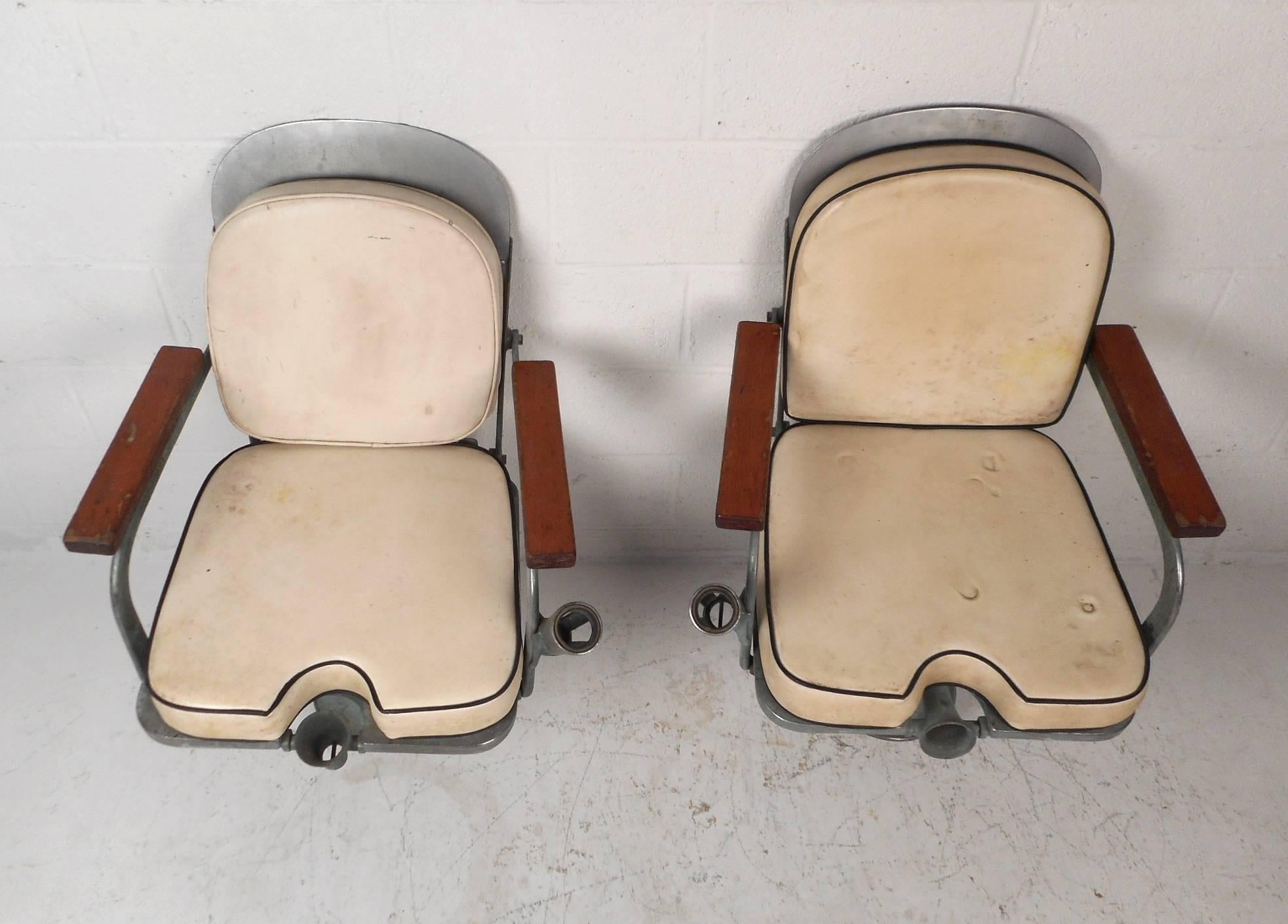 This beautiful pair of vintage boat chairs feature a heavy duty steel frame with wooden arm rests. This comfortable and sturdy pair of chairs have thick custom cushions. Unique design with a conveniently placed fishing pole holder on the side. This