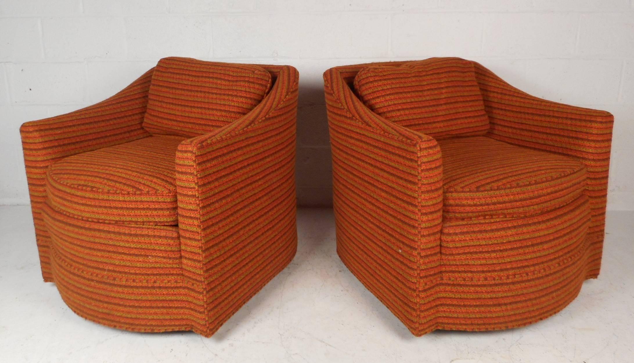 This beautiful pair of vintage modern lounge chairs feature plush orange upholstery and thick padded cushions ensuring plenty of comfort. Sleek design with sloping arm rests, a rounded front, and wide seating. This unique pair sits on top of wheels