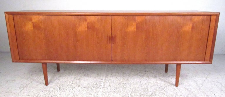 Nicely detailed tambour door sideboard/credenza featuring two adjustable shelves, four felt lined trays, and a finished teak back. Produced by Faarup Mobelfabik, Denmark. Please confirm item location (NY or NJ) with dealer.