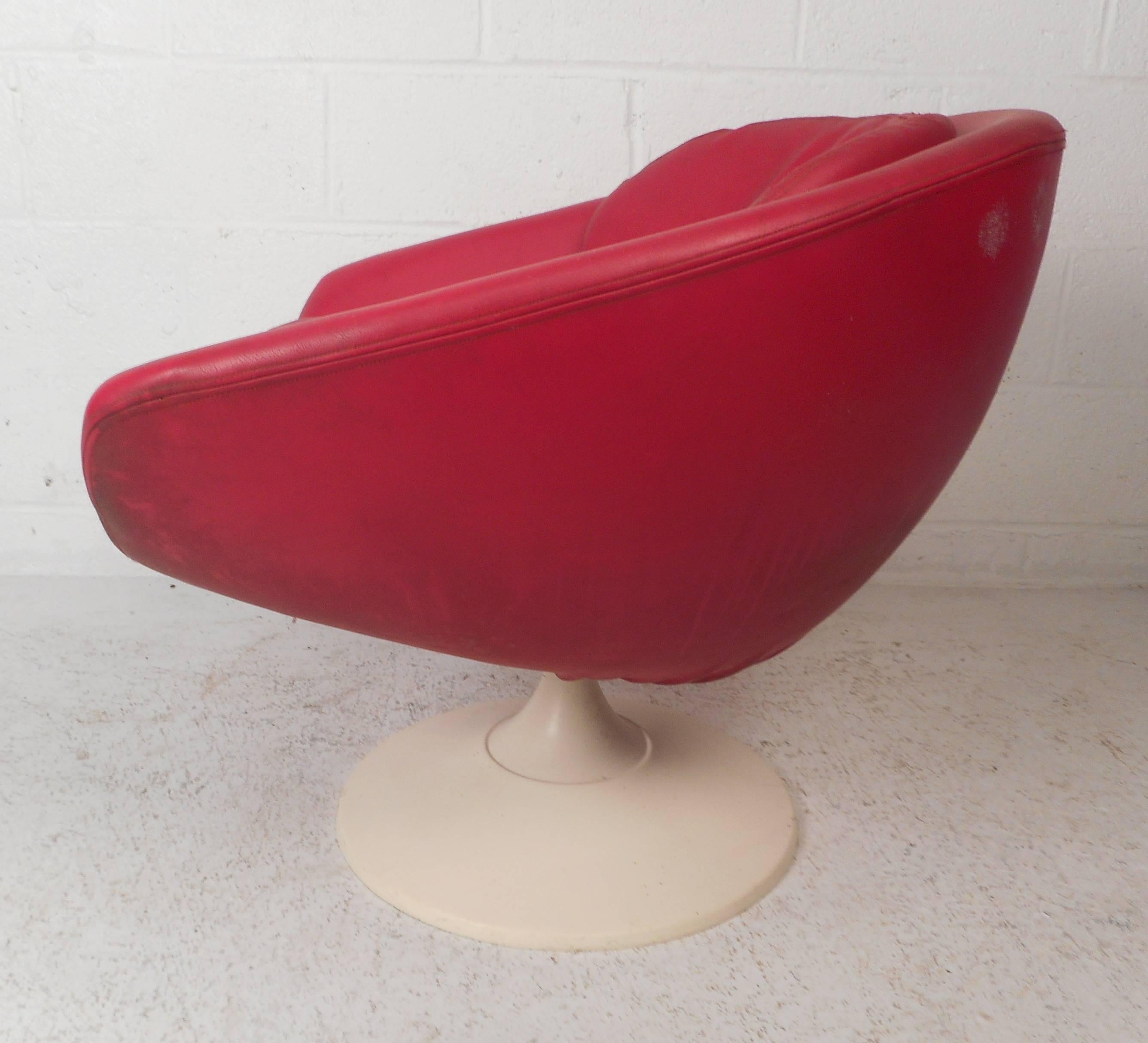 This gorgeous vintage modern lounge chair features a unique tulip shaped base. This unique chair has two overstuffed removable cushions covered in a red vinyl. Sleek and comfortable design with wide seating and the convenient ability to swivel. This