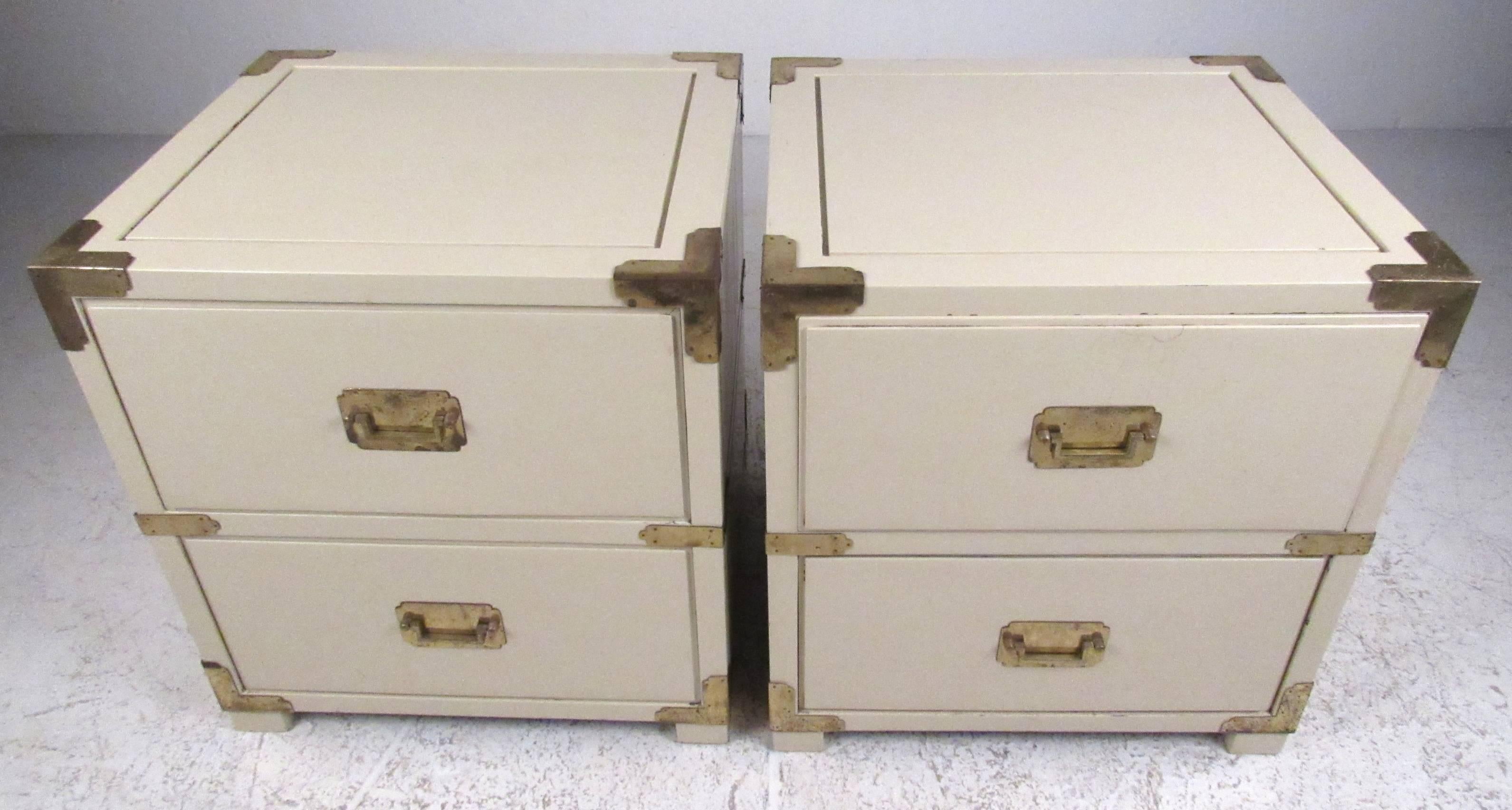 Attractive pair of crème color two-drawer Campaign style cabinets with brass hardware and finished backs. Perfect for use in a nightstand or end table application. Please confirm item location (NY or NJ) with dealer.