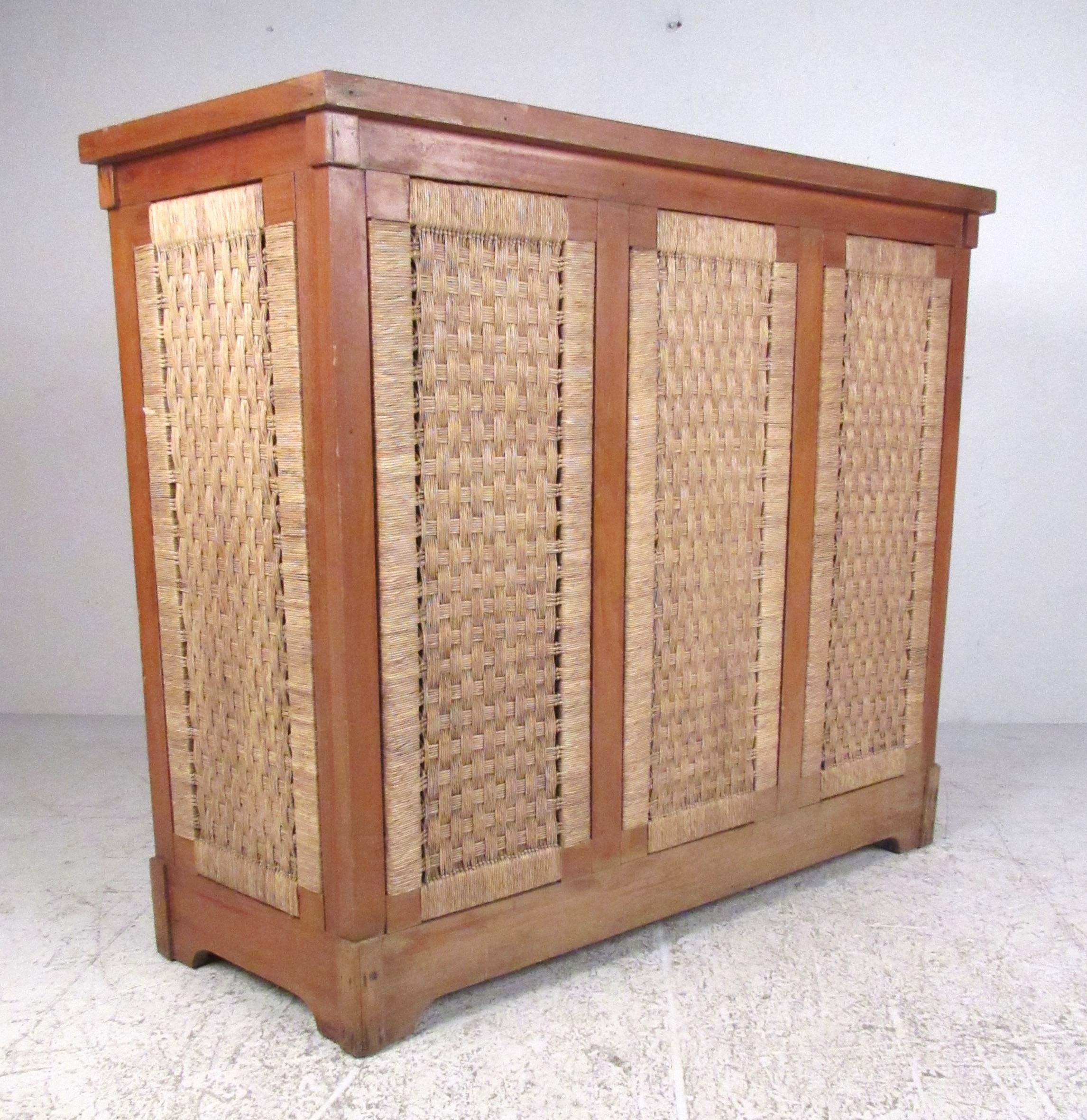 Unique freestanding dry bar constructed from tropical hardwood with woven rattan accent panels. Suitable for interior or exterior application, the bar offers both open and enclosed storage shelves and three rattan covered matching stools. Please