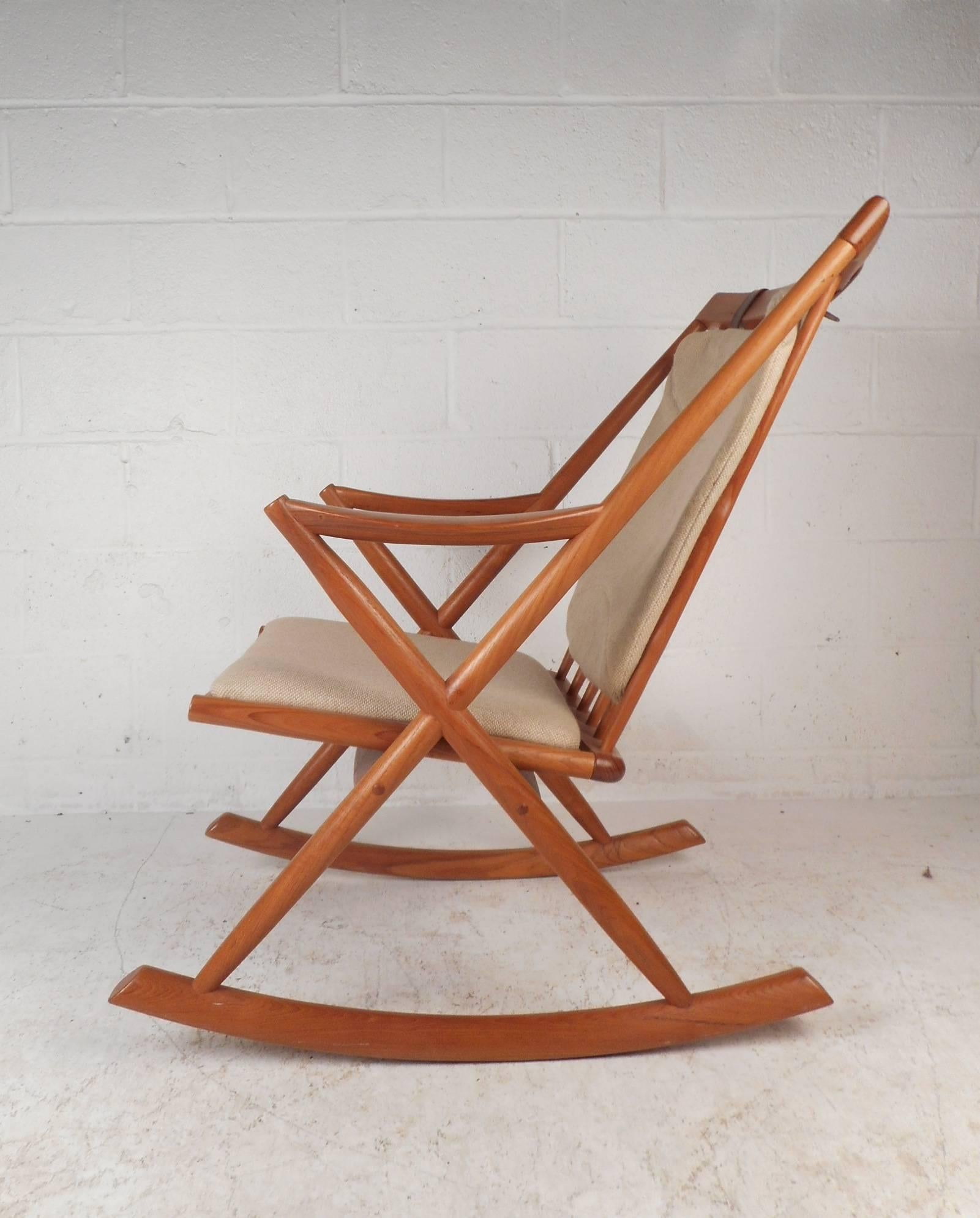 This beautiful vintage modern rocking chair features a solid teak frame with unique “X” shaped sides. Exquisite seating with a thick padded cushion and a cushion attached to the backrest with leather straps holding it in place. This comfortable