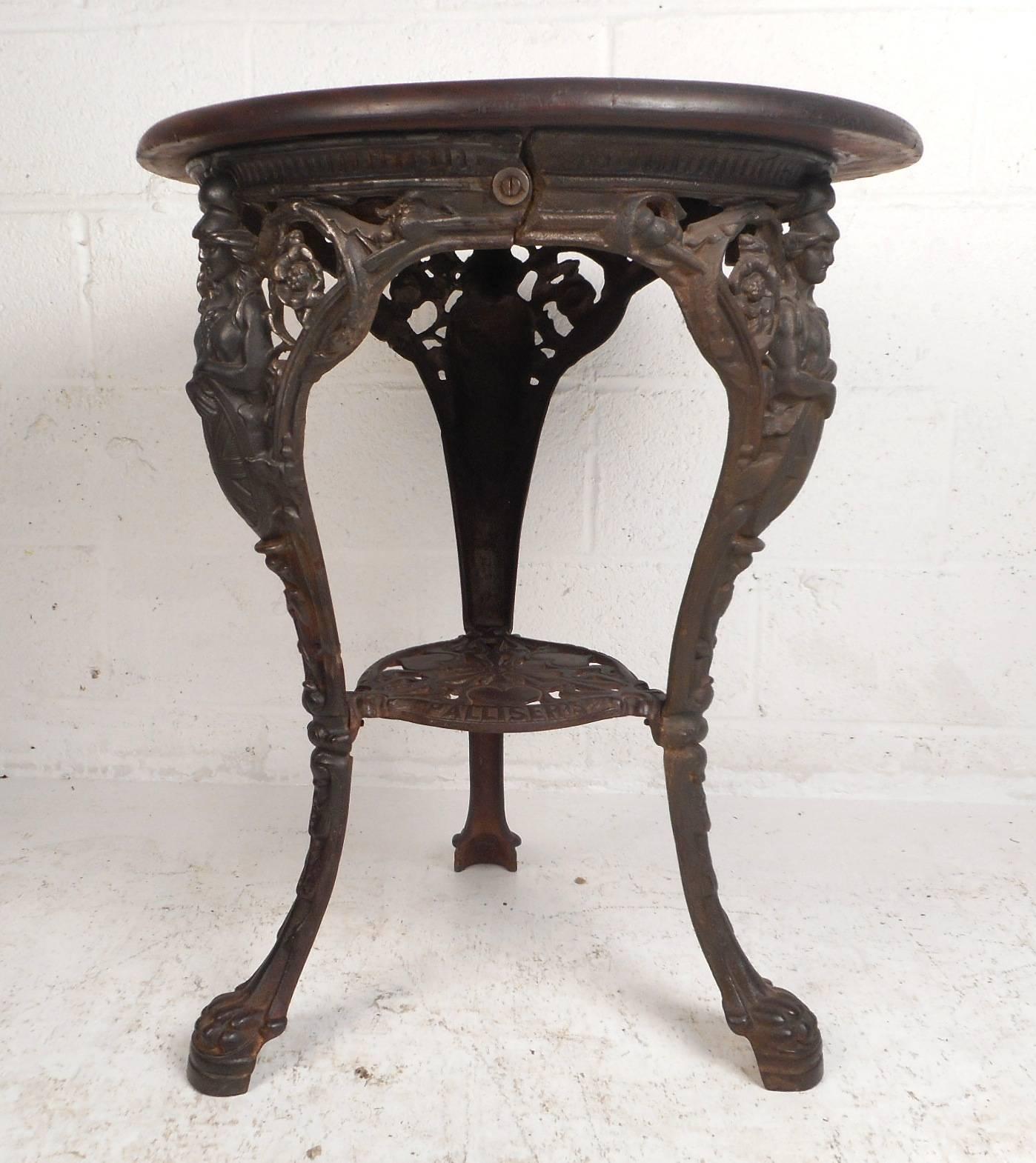 This beautiful vintage side table features a unique cast iron base with excellent detail. This exquisite piece has curved legs with paws as feet and floral designs throughout. The solid wood top shows true quality making this one of a kind side