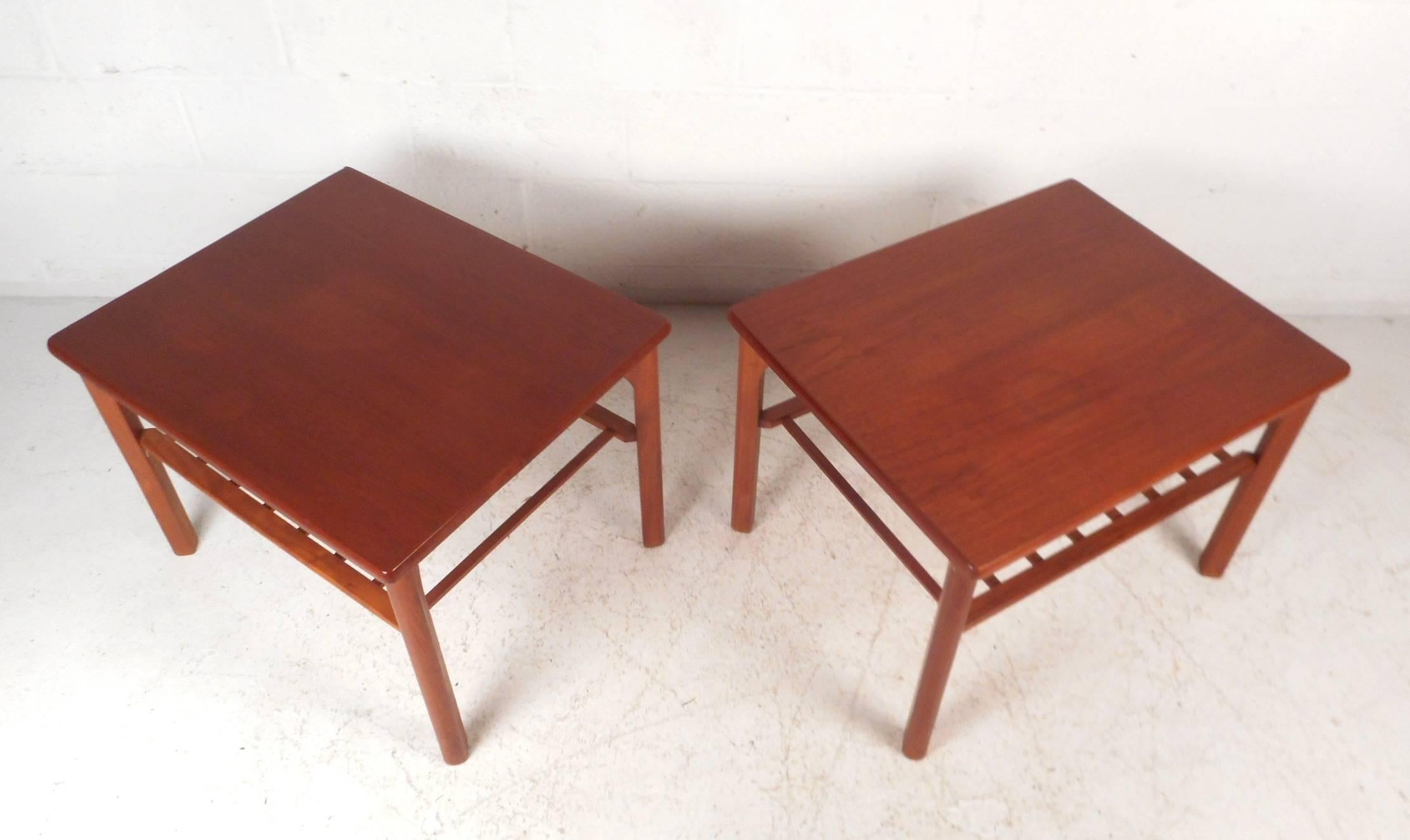 This fabulous pair of vintage modern end tables feature a lower slatted tier for added storage. Sleek design was made in Denmark by Mobelfabrik Toften and has elegant teak wood grain throughout. These lovely side tables have smooth rounded edges and