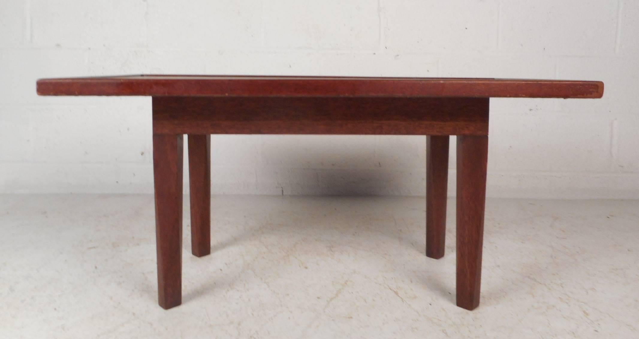 Fabulous vintage modern coffee table with raised edges around the top and long tapered legs. The unusual size of this piece allows it to function as a coffee table or an end table. The sleek and sturdy design features gorgeous dark walnut wood grain