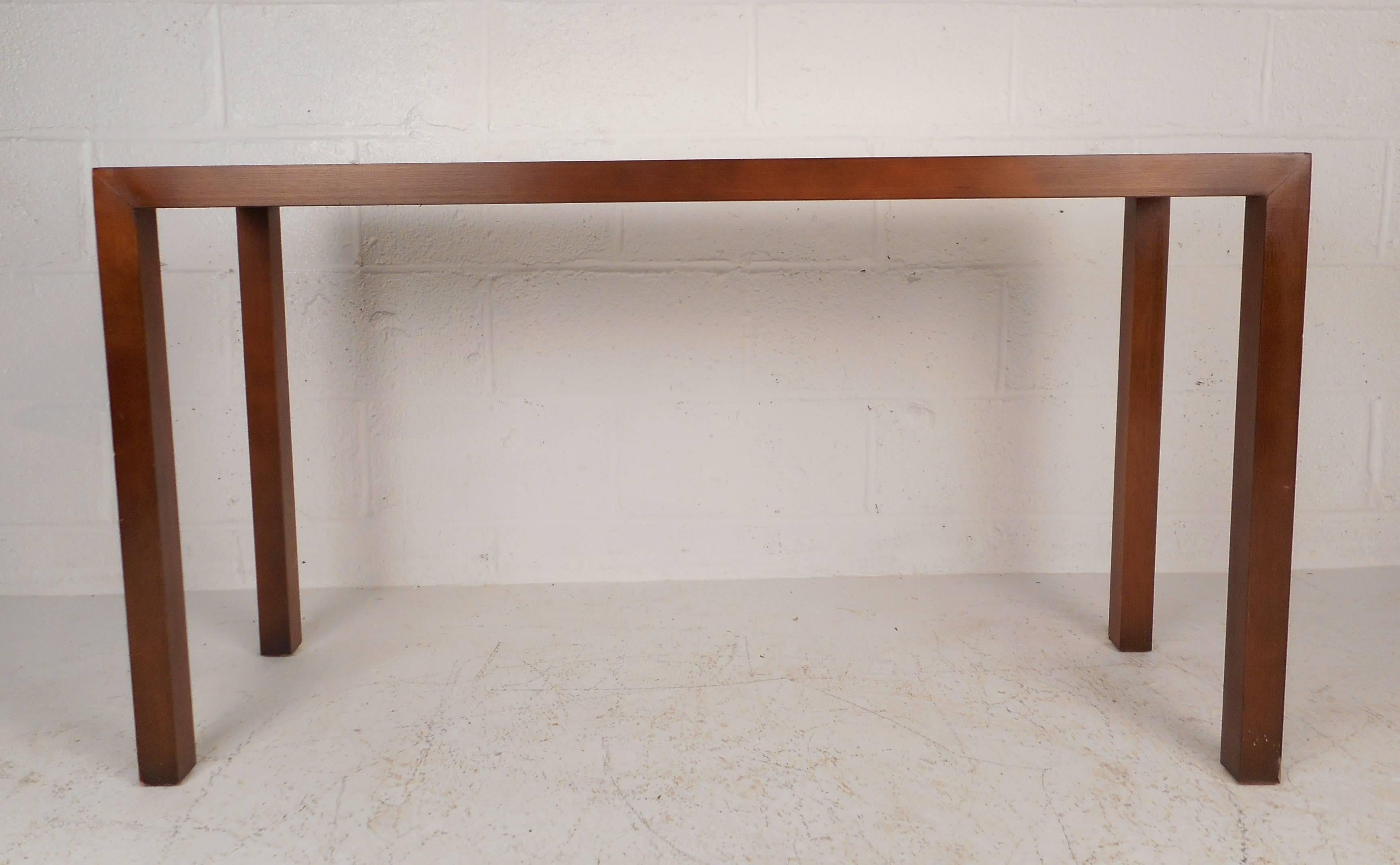 This beautiful vintage modern console table has four long sturdy legs and a rectangular top. Sleek design with gorgeous wood grain on top running in different directions. This stunning midcentury walnut hall table makes the perfect addition to any