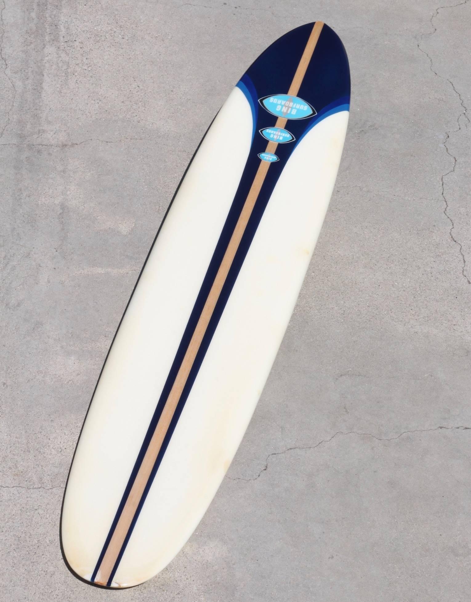 Rare fully restored, triple logo, 1963 bing surfboard. This striking pin-tail board has a 1.5 inch wide balsa stringer and a chop-stick laminated fin. Amazing graphics feature three blue tones set against creamy-white, centered on the balsa stringer