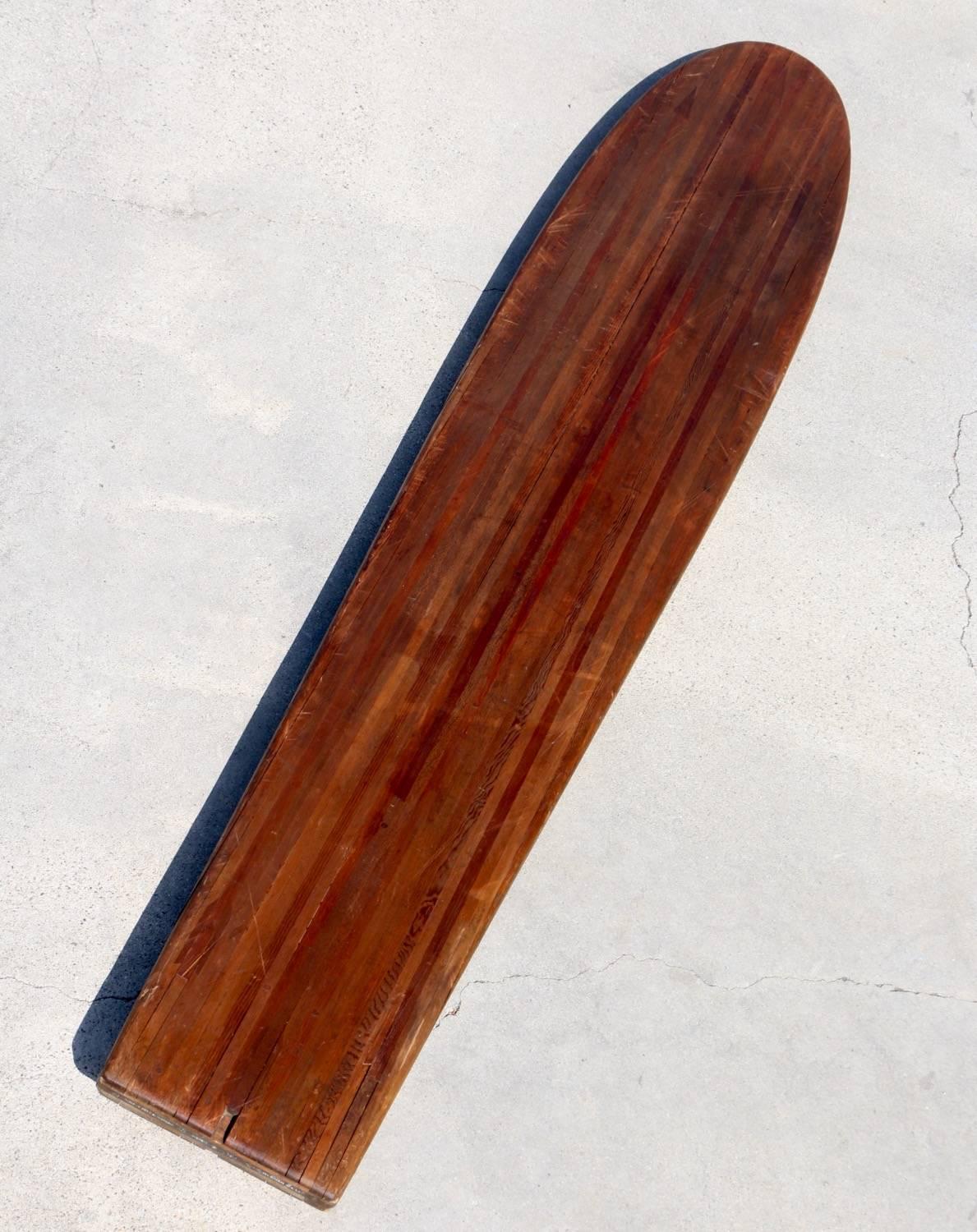 Antique wood surfboard, 1935, all original, made in Los Angeles. This board is an exceptional beauty. Solid wood strips displaying the natural patina and original finish are masterfully held together with dowels. A variety of woods with arrows in a