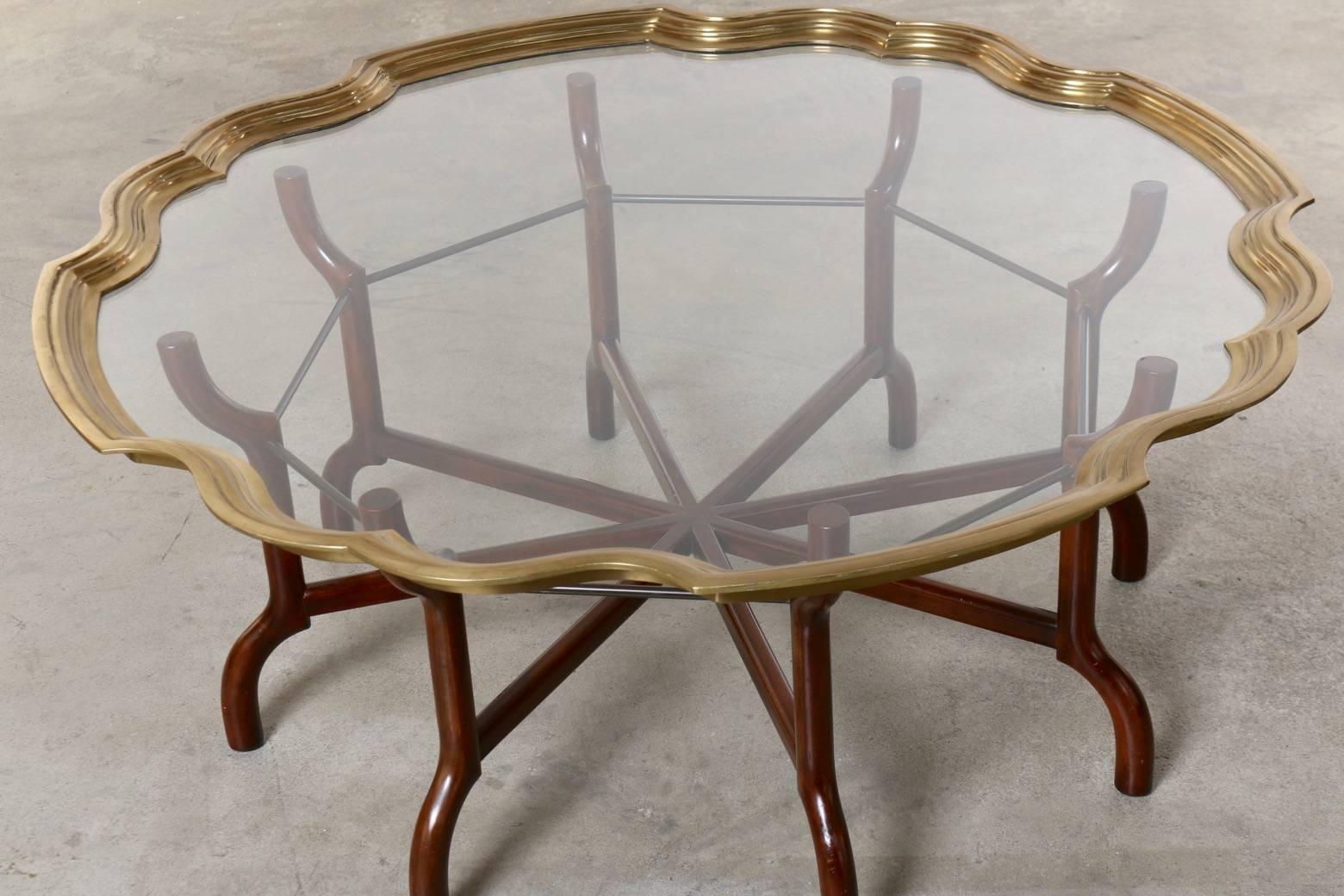 Architectural styling and artistry were combined by Baker to create this unique and stunning version of the classic tray top coffee table.  The brass is artfully cast to create a ribbon effect, holding the glass.  The design of the folding base