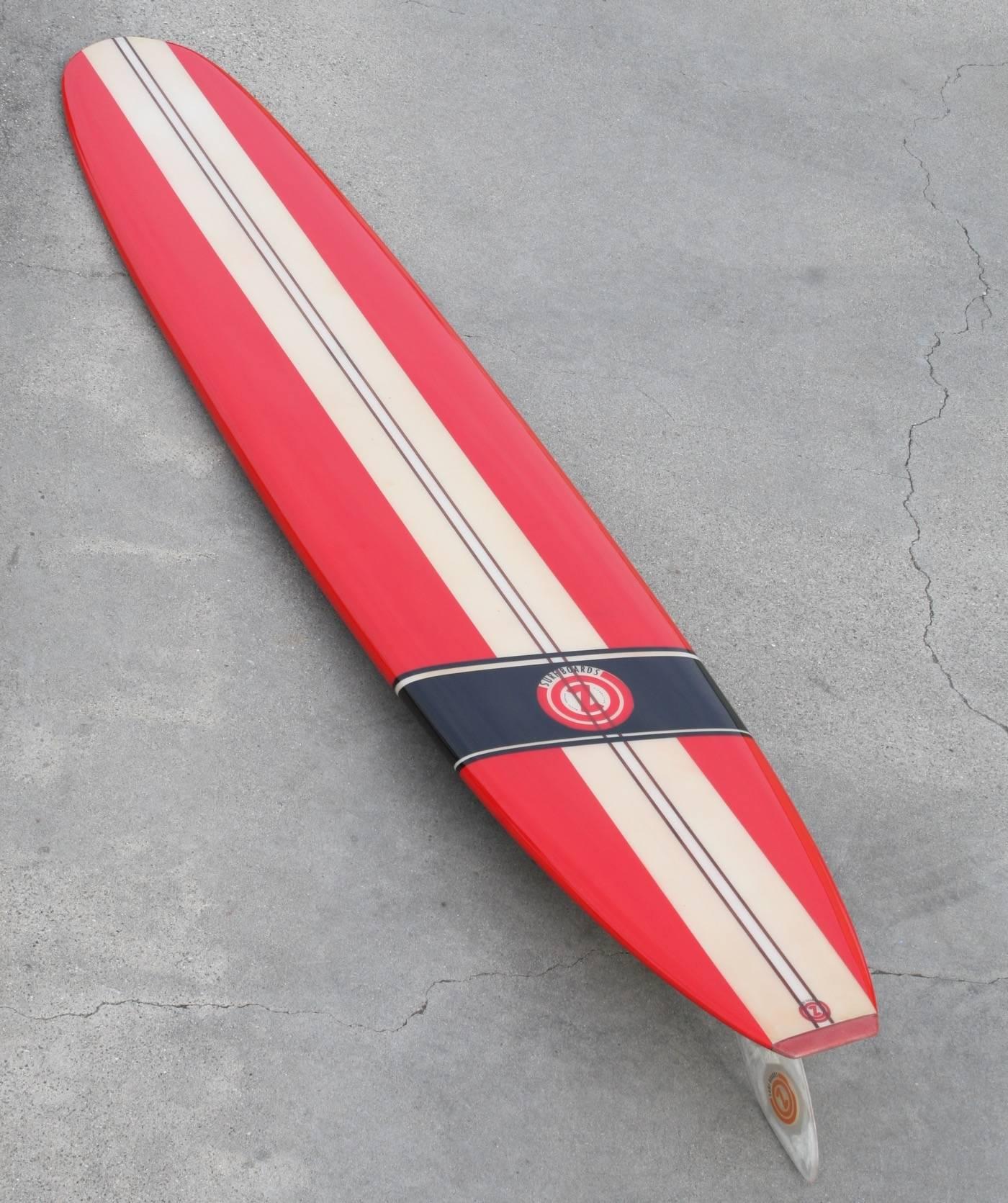 Made in Santa Monica California in the mid-1960s this fully restored, 9 foot 3 inch, Con surfboard is simply stunning. Brilliant red is accented with wide creamy white horizontal stripes with a deep ebony diagonal stripe anchoring the Classic Con