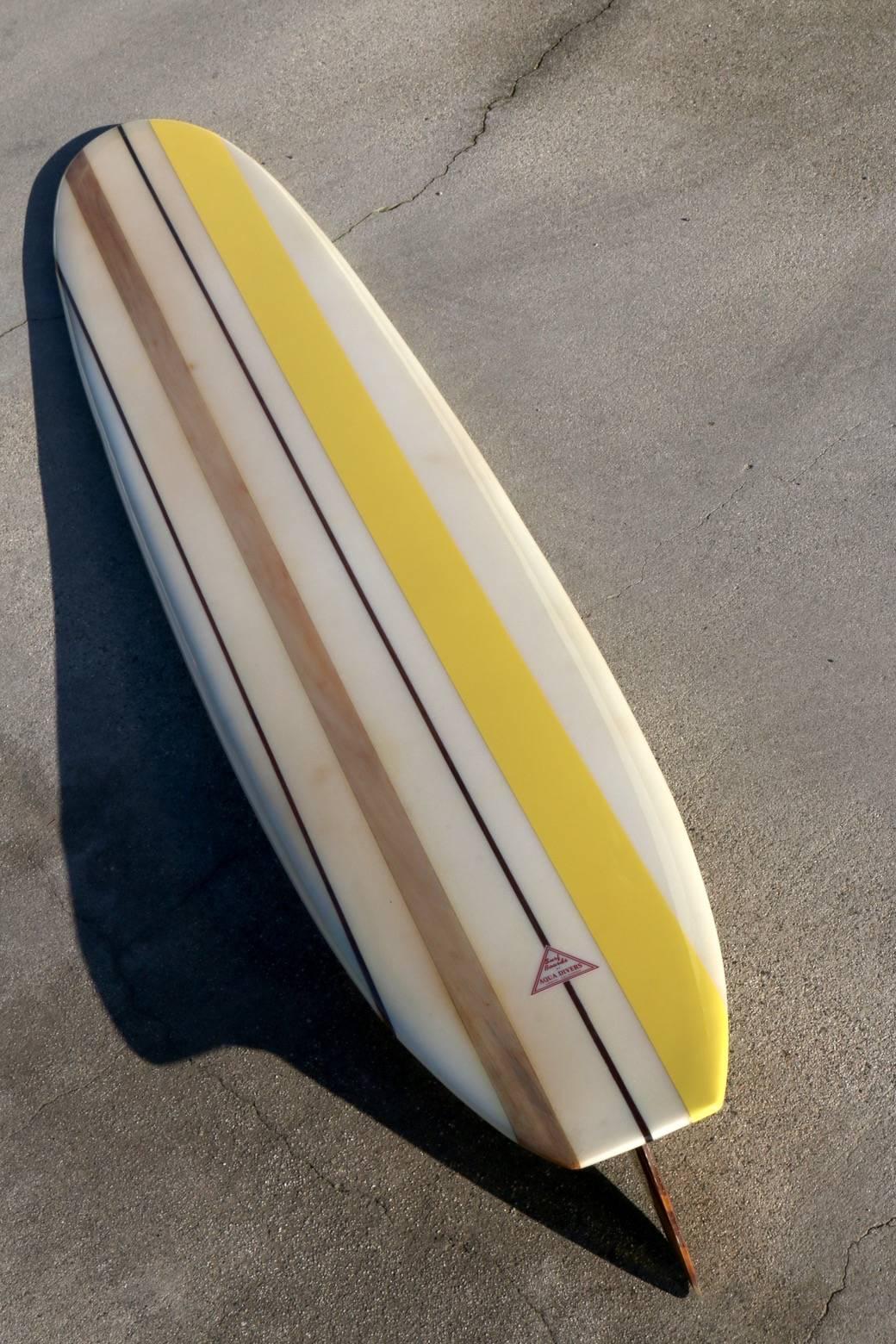 Fully restored early 1960s Surfboard by Aqua Divers, Lomita CA, Extremely Rare. At 9 foot, 6 inches long this early 1960s, creamy white longboard with wonderful accents offers a majestic presence. It's striking to view from all angles and looks
