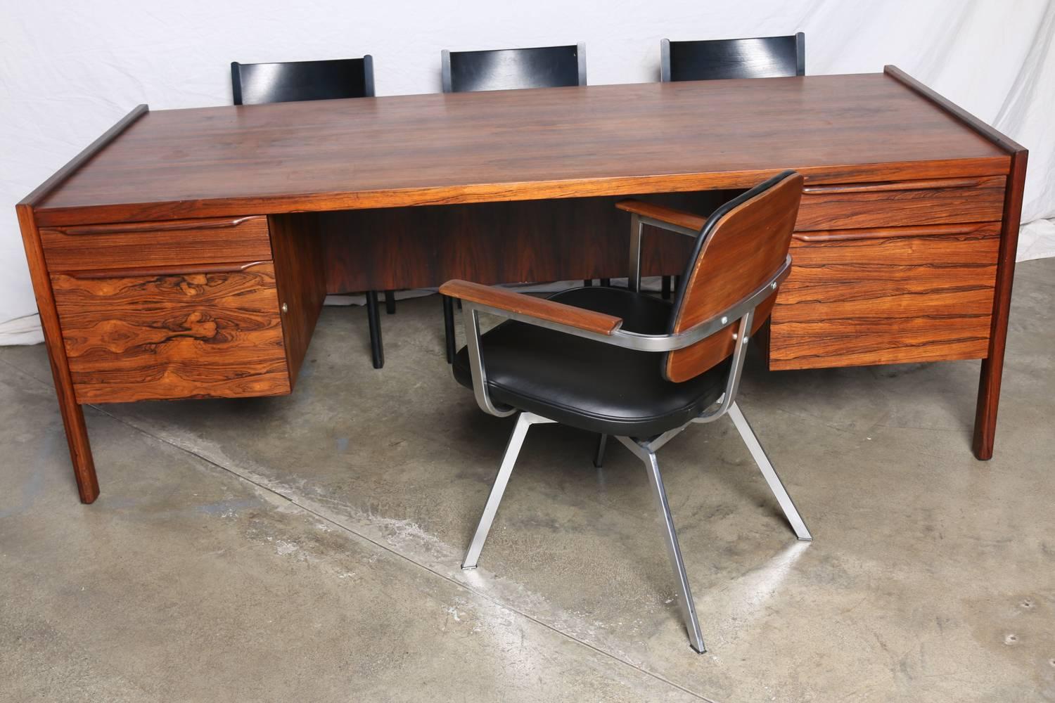 Oversize Rosewood Executive Desk, architectural lines, quality construction, musical rosewood grain pattern.  Purchased in Beverly Hills in the 1960s. Four drawers, a wide opening for seating, desk top overhangs on rear, permitting it to be shared