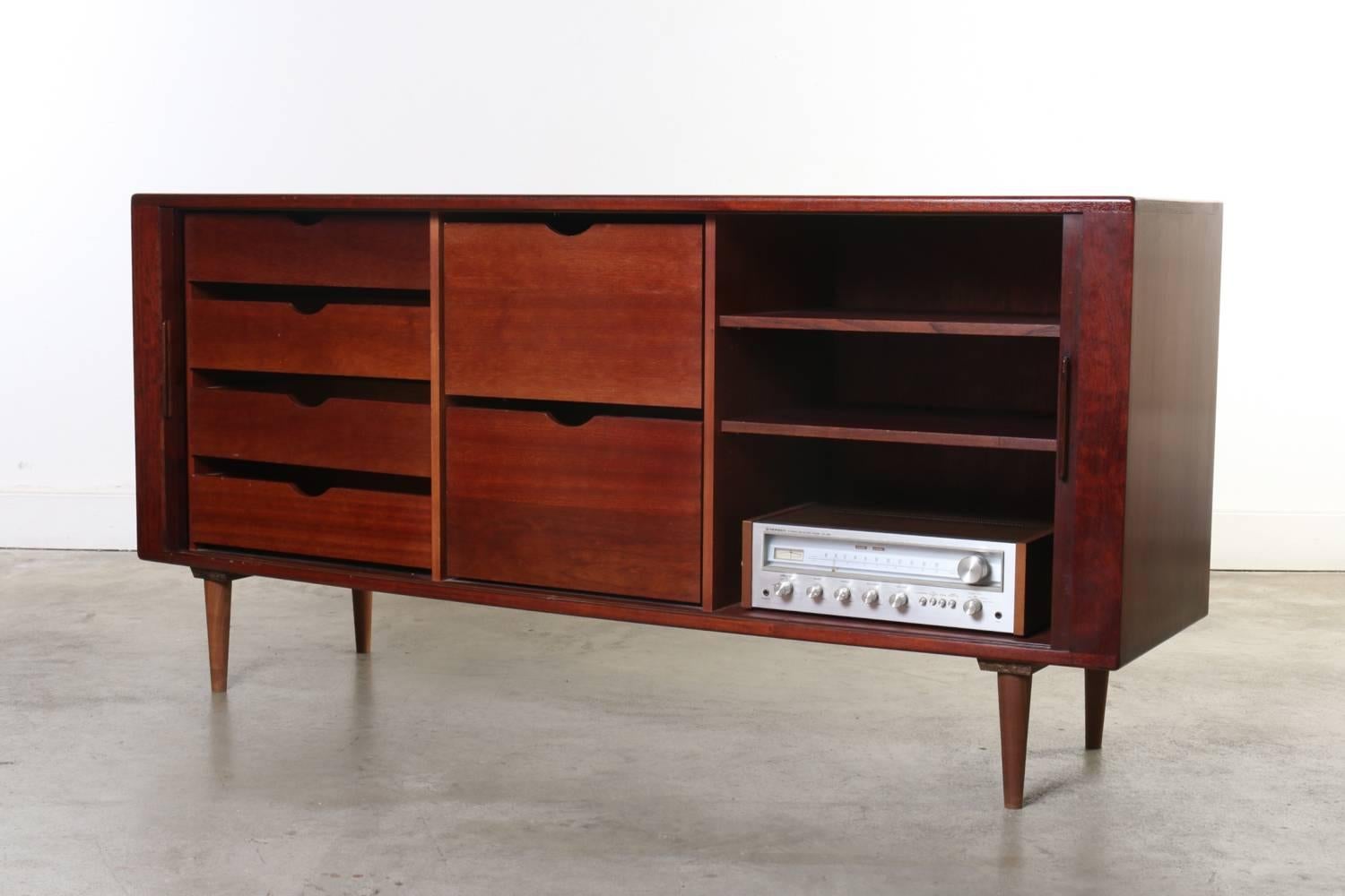 This rosewood credenza is clearly stamped on the back made in Denmark by H. P. Hansen, it features sliding tambour doors, interior shelves, four storage drawers and two file drawers. Great for home or office. This beauty is in excellent original