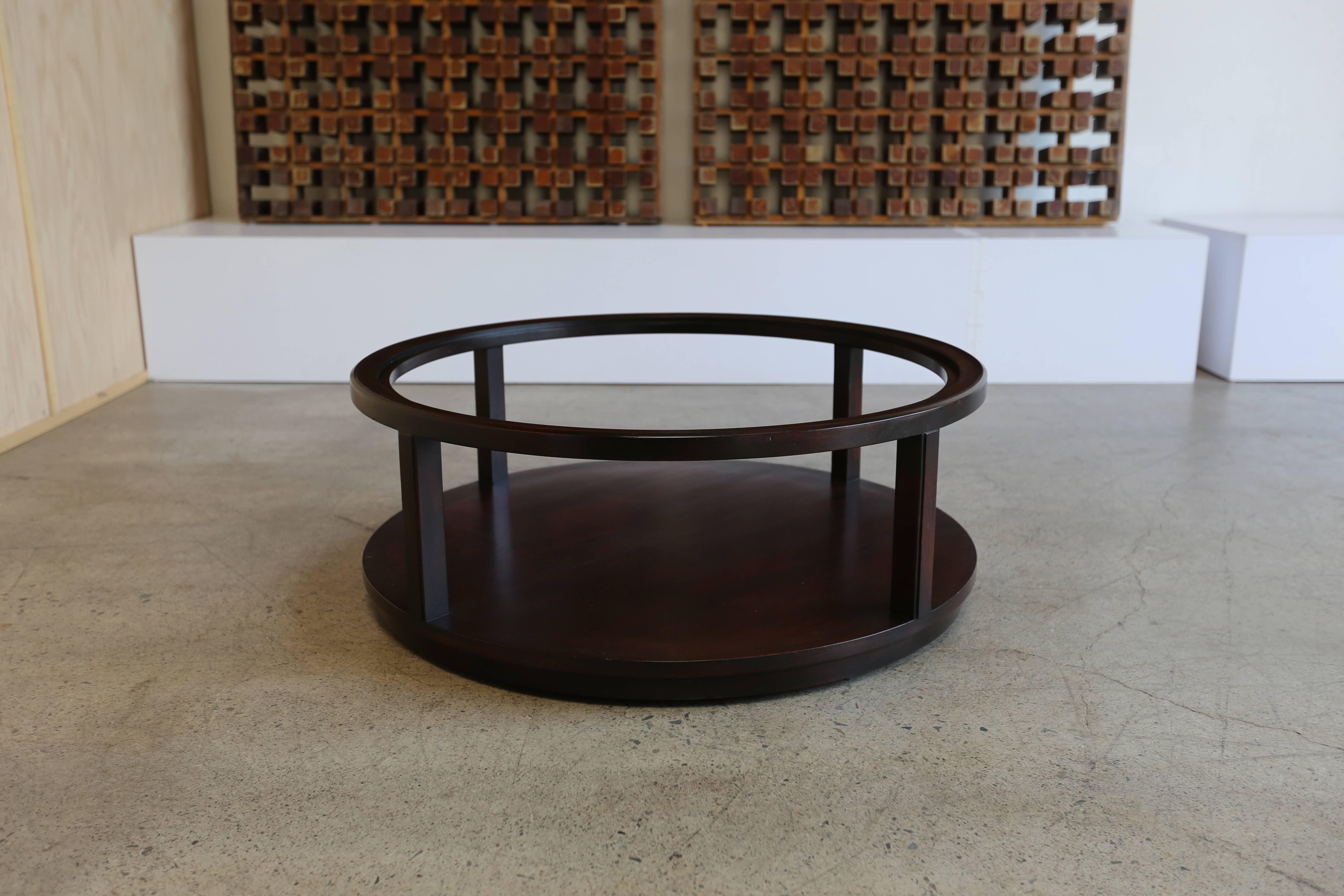 Round dark stained mahogany and glass coffee table by Edward Wormley for Dunbar. This piece has hidden castors. Signed to the bottom.