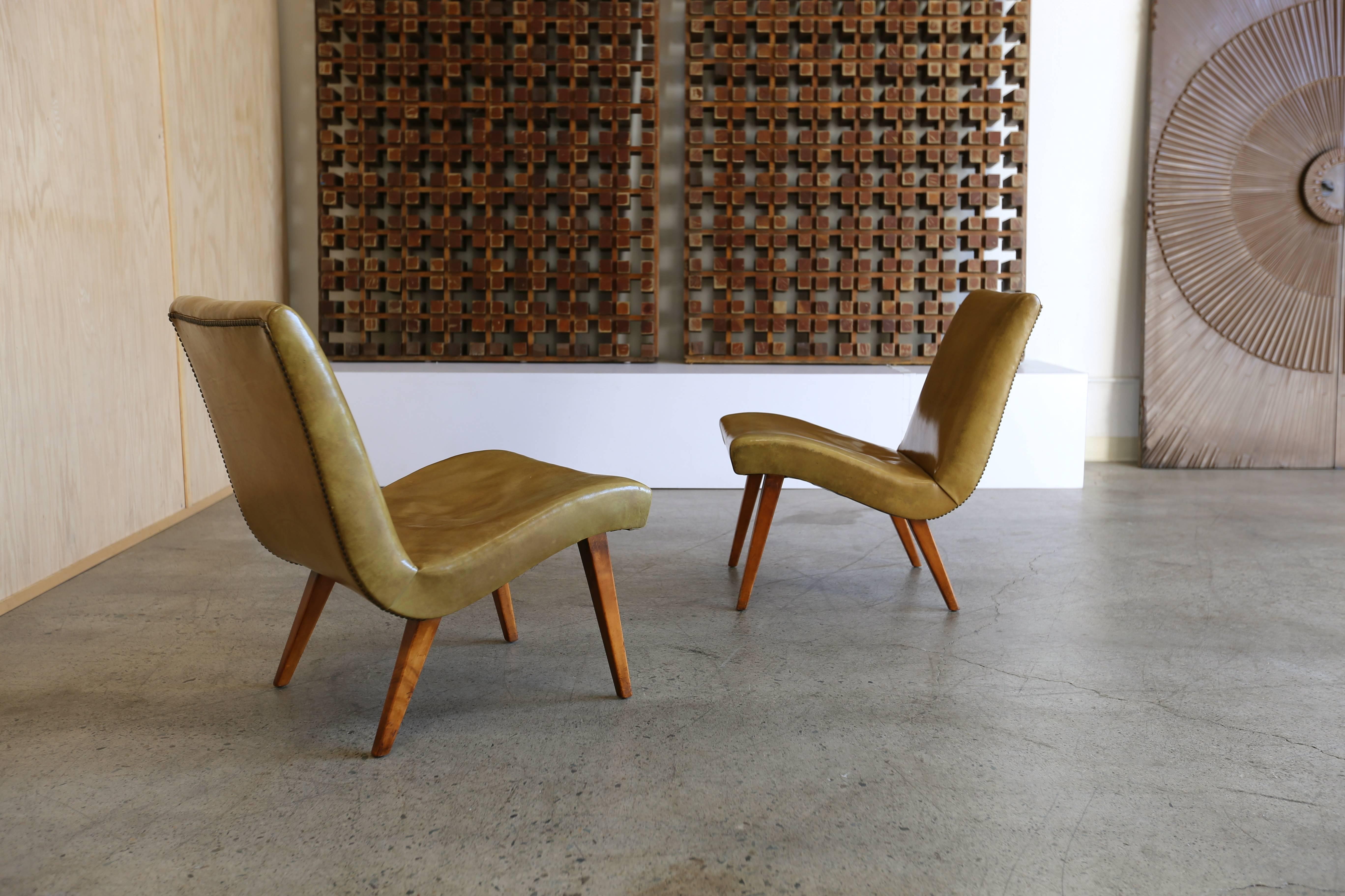 Early pair of lounge chairs by Jens Risom for Knoll. Patina to the original leather and birchwood.