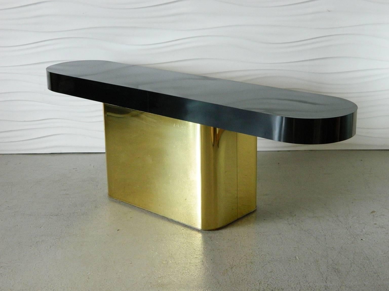 Designed by Milo Baughman for Thayer Coggin, this console table has a base wrapped in a brass finish and a black glossy laminate top. Two fully-upholstered stools nest underneath to provide additional seating. The stools measure 22.5