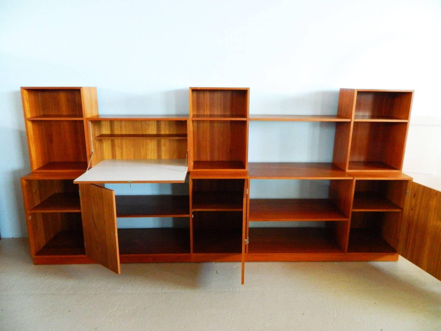 This Cresco teak wall system by Finn Juhl consists of two base pieces, three cabinets with doors, three open cabinets, a drop-front desk, six small shelves and four large shelves. 

Lower cabinets are 18.5