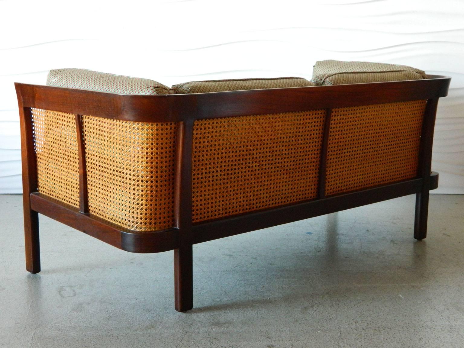 This handsome caned settee by Erwin-Lambeth features a curved walnut frame and original caning. 

In addition to the seat cushion, the settee also has two back cushions and two-side cushions.