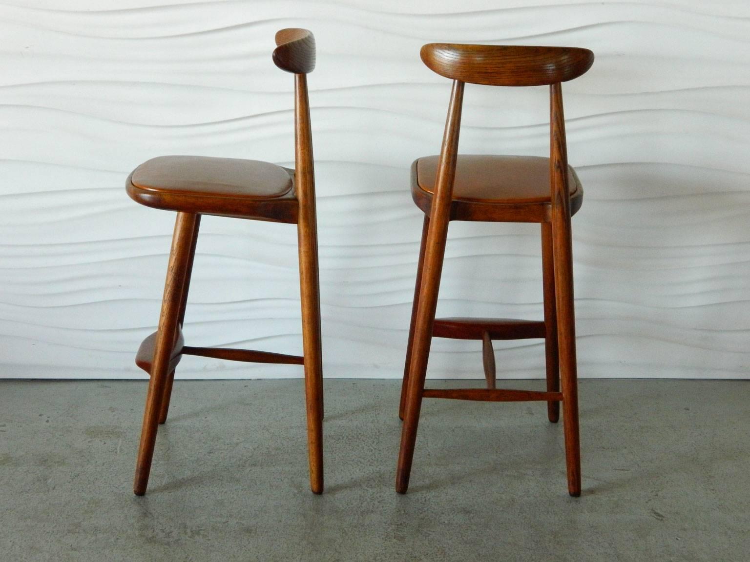 Designed by Danish architect Vilhelm Wohlert in the 1950s, this handsome pair of oak stools have teak footrests and leather-covered seats.