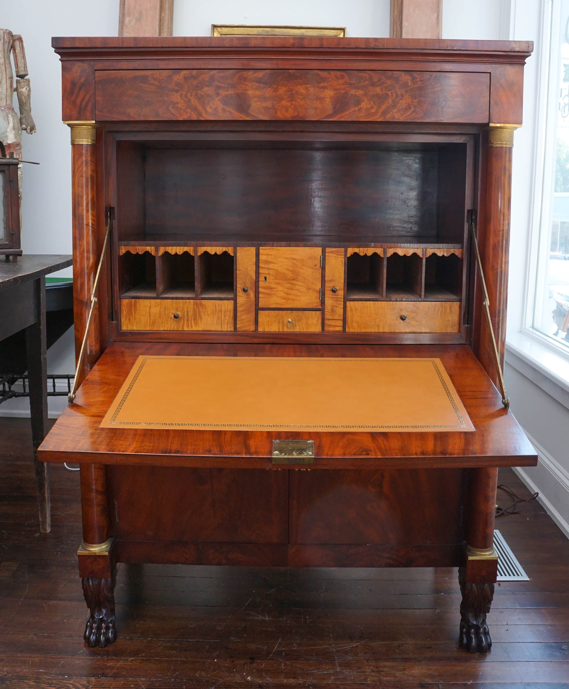Beautifully bookmatched mahogany veneers and satinwood veneered interior drawers. Imported original French ormolu. Veneered columns in the manner of Lannuier and paw feet in the manner of Phyfe.
Repairs to mahogany top; new Greek key motif leather