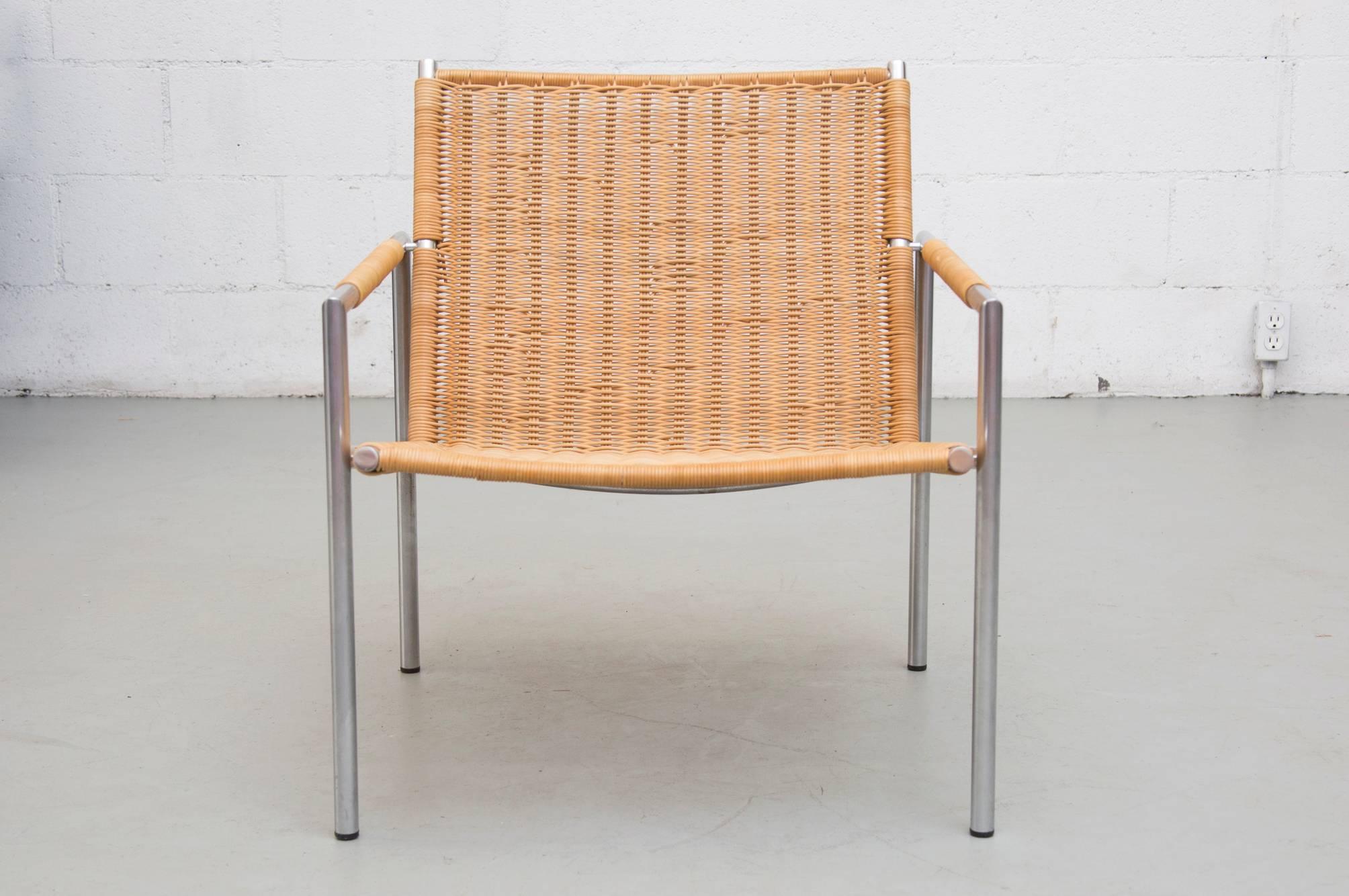 One of Martin Visser's well-known lounge chair designs of the 1960s. Lounge chair with tubular chrome metal frame and woven rattan seat and back, with rattan wrap detailing on armrests. In good original condition with visible signs of wear to the