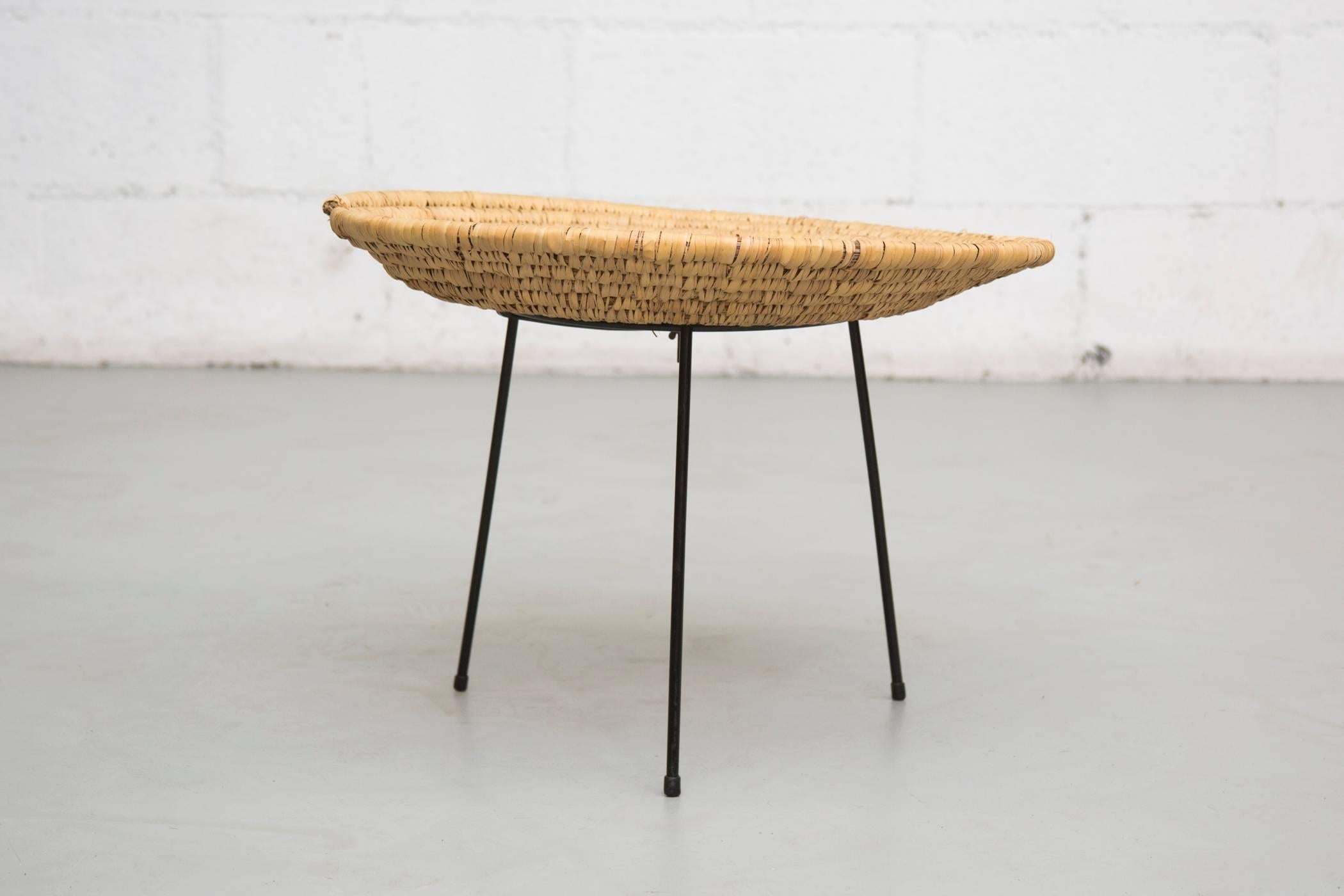 Woven rush side table, tray-basket bolted on a black enameled wire frame. In original condition with slight slumping and some wear to the frame consistent with age and use.