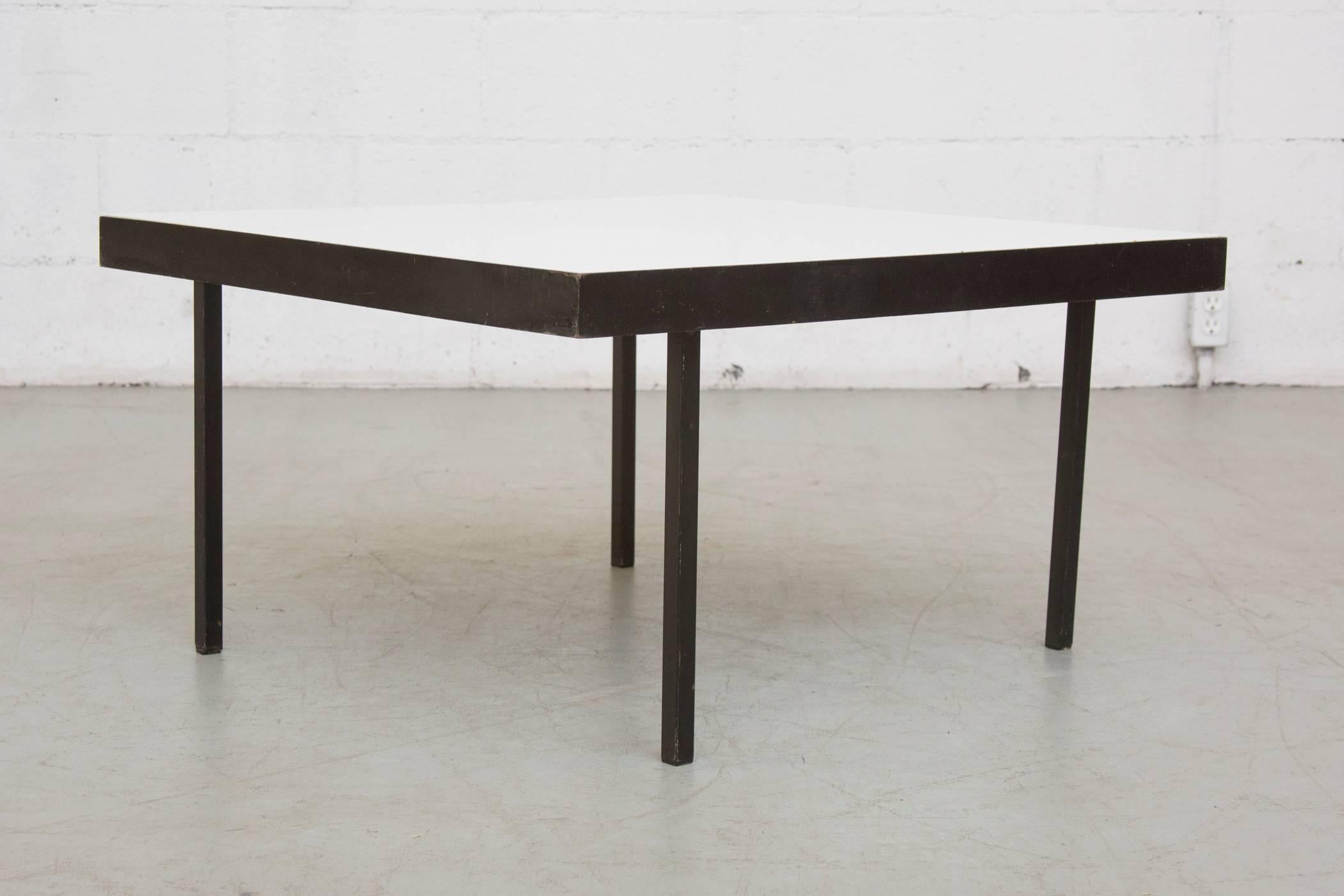 Minimal black enameled framed coffee table with original opaque white glass top and offset legs. In the style of Janni Van pelt. In original condition with wear consistent with age and use.