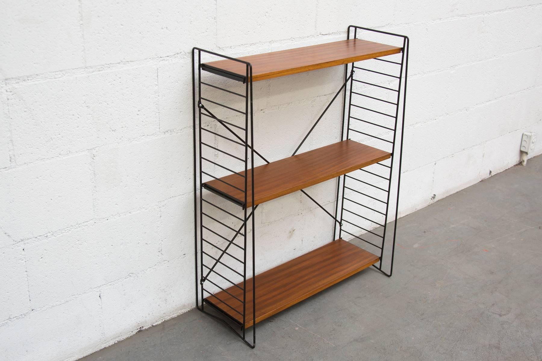 Super smart and sleek standing teak and metal bookshelf unit. Shelves are movable. These units can be flat packed for shipping. Original condition, with some wear.