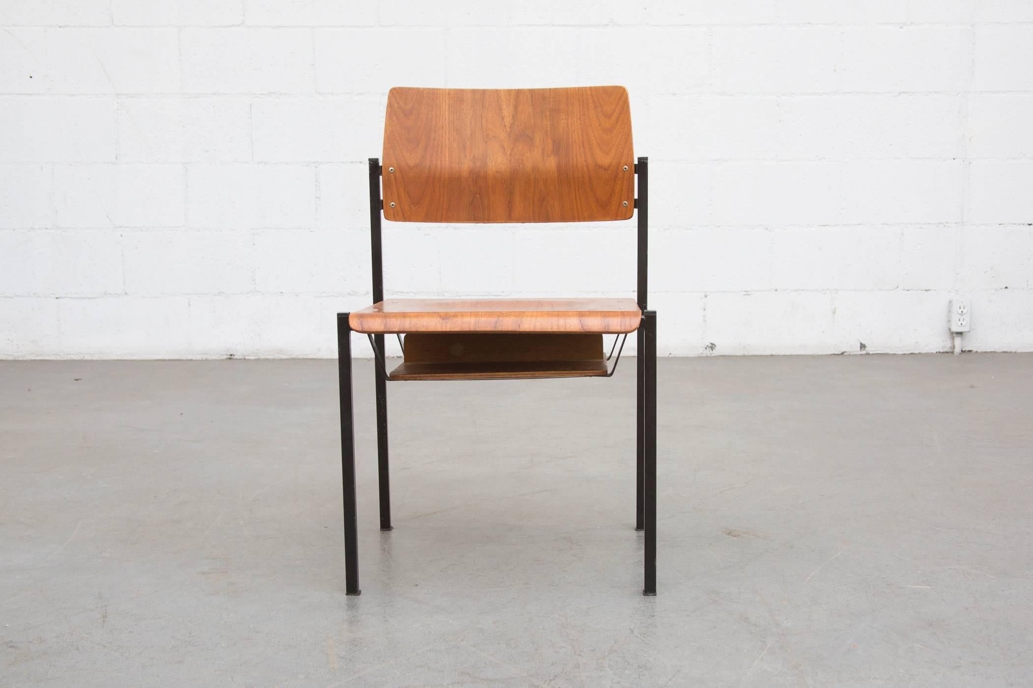 Schön konstruierte Stapelstühle aus Teakholz mit schwarz emailliertem Metallrahmen und Bücherfach unter dem Sitz. Im ursprünglichen Zustand mit einigen sichtbaren Verschleiß an Holz und Rahmen im Einklang mit Alter und Nutzung.