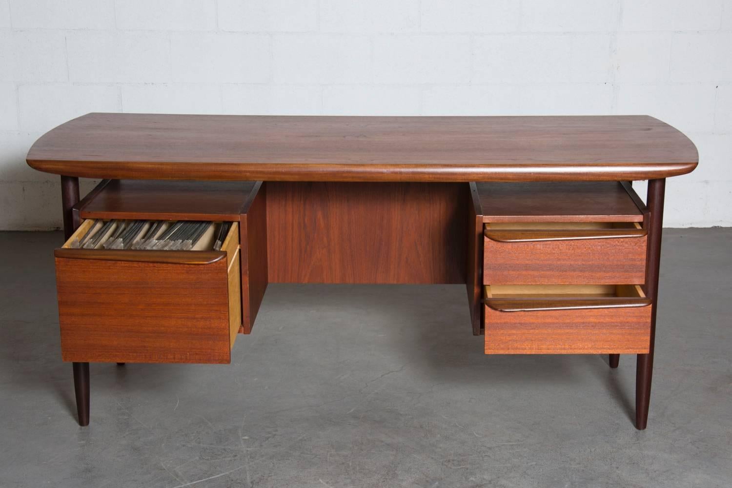 Beautiful dark teak desk with organic drawer pulls, floating top, exposed bookcase, and one large filing drawer. In original condition, some chipping and wear consistent with age and use.
 