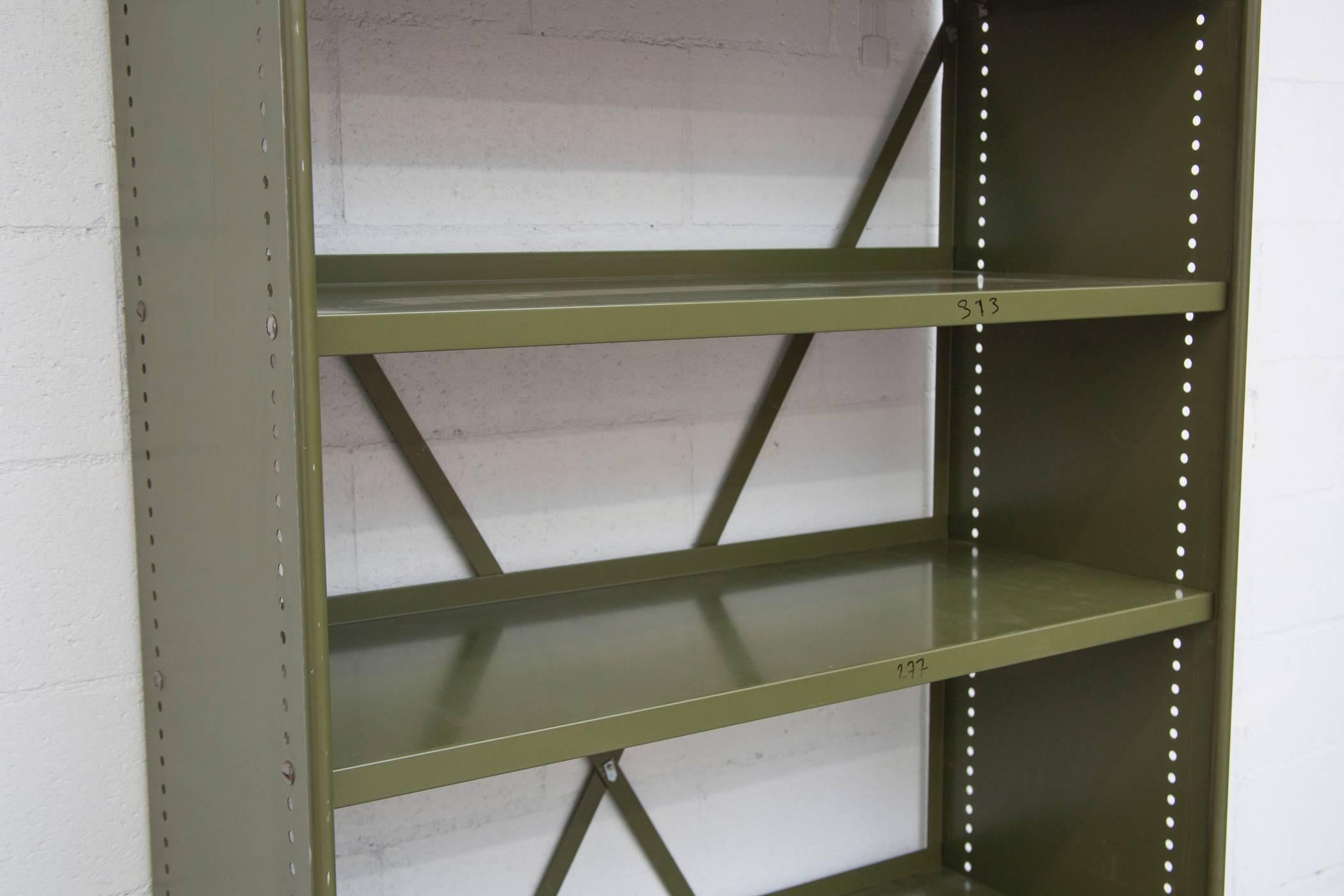 Extra tall Industrial bookshelf in great army green finish. Original vintage condition, with visible wear and signs of use. Some scratching and slight denting, consistent with its age and usage. Shelves are adjustable. Two available.
