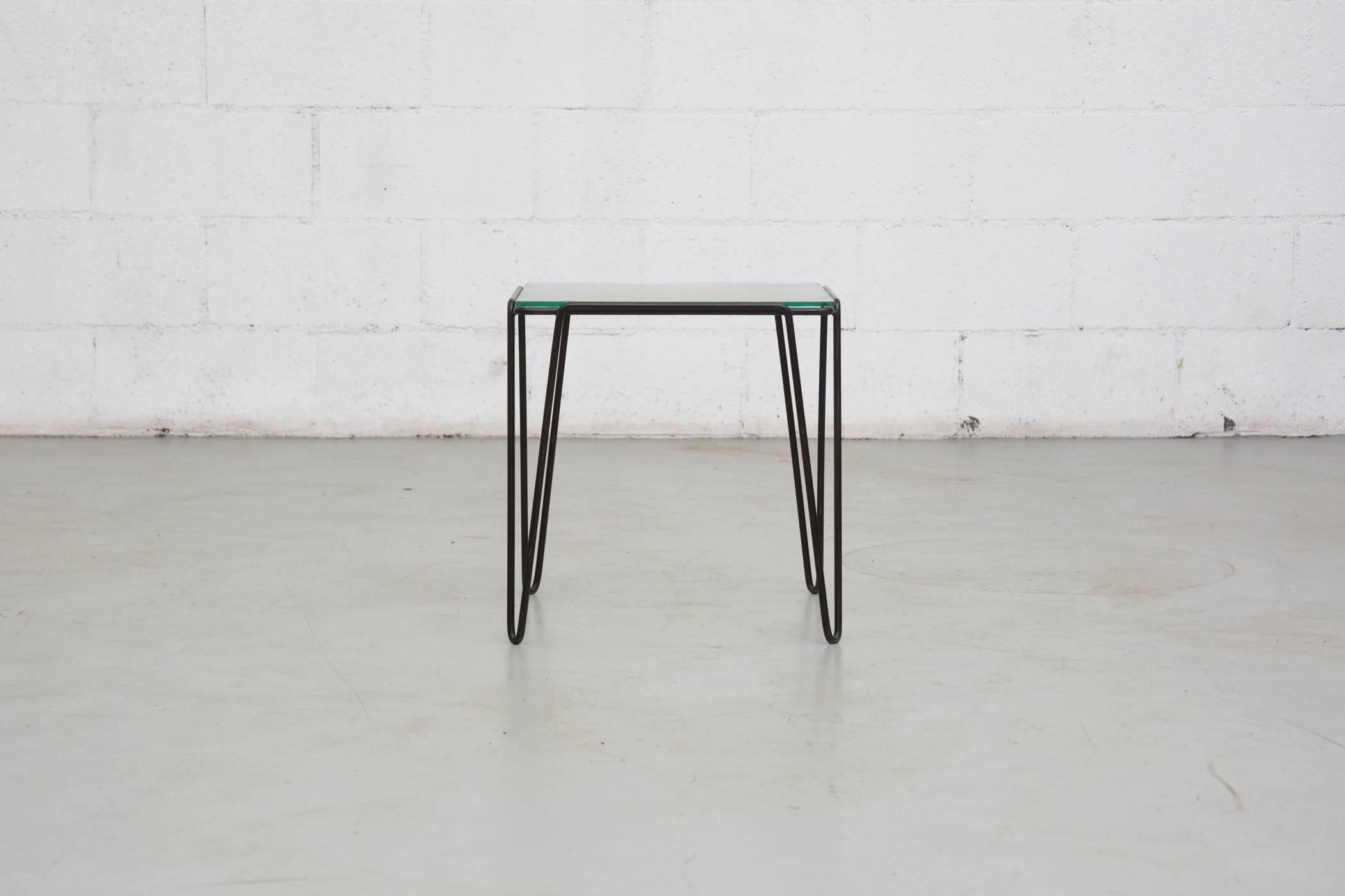 Black metal frame with hairpin style leg and textured glass top. This series of tables was designed during the 1950s by Arnold Bueno de Mesquita and manufactured in the Netherlands by Spurs Meubelen. Visible wear to frame and glass, consistent with