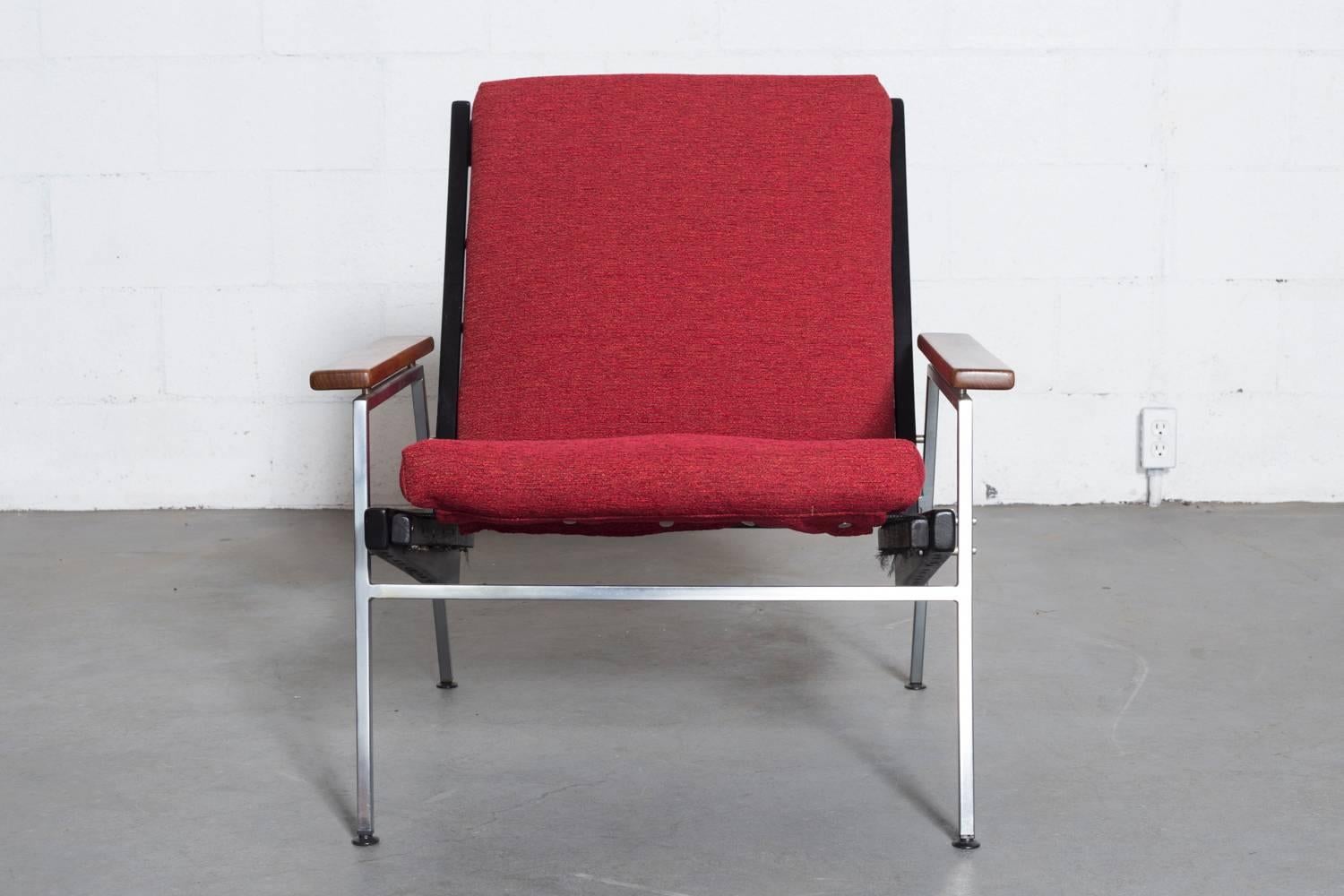 Great architectural lines. Ebonized teak frame and armrests with square metal frame and newly upholstered cushion in garnet red. Frame in original condition with visible signs of wear.