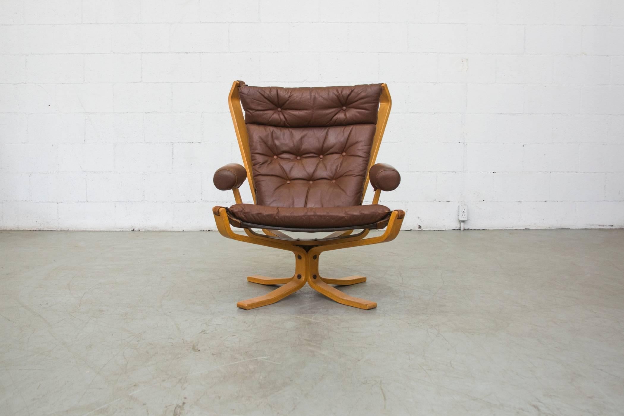 This erly seventies beauty is modeled after Sigurd Ressell 's 'Falcon' high back chair as it was produced by Vatne Møbler. The original brown leather body is buckled onto a dramatic, bent beechwood frame. Original condition.