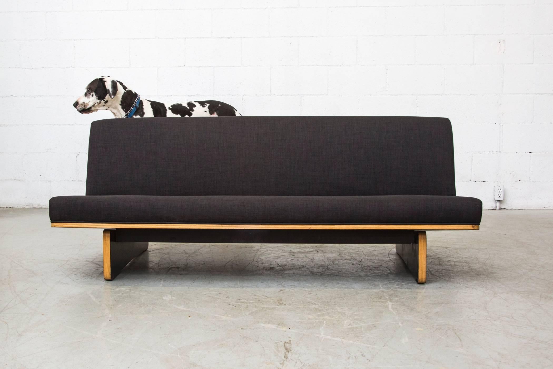 Newly reupholstered rare three-seat Kho Liang le sofa in almost black fabric with black lacquered laminated plywood base. Base is original and shows light scratching to black laminate and wood consistent with age and use.