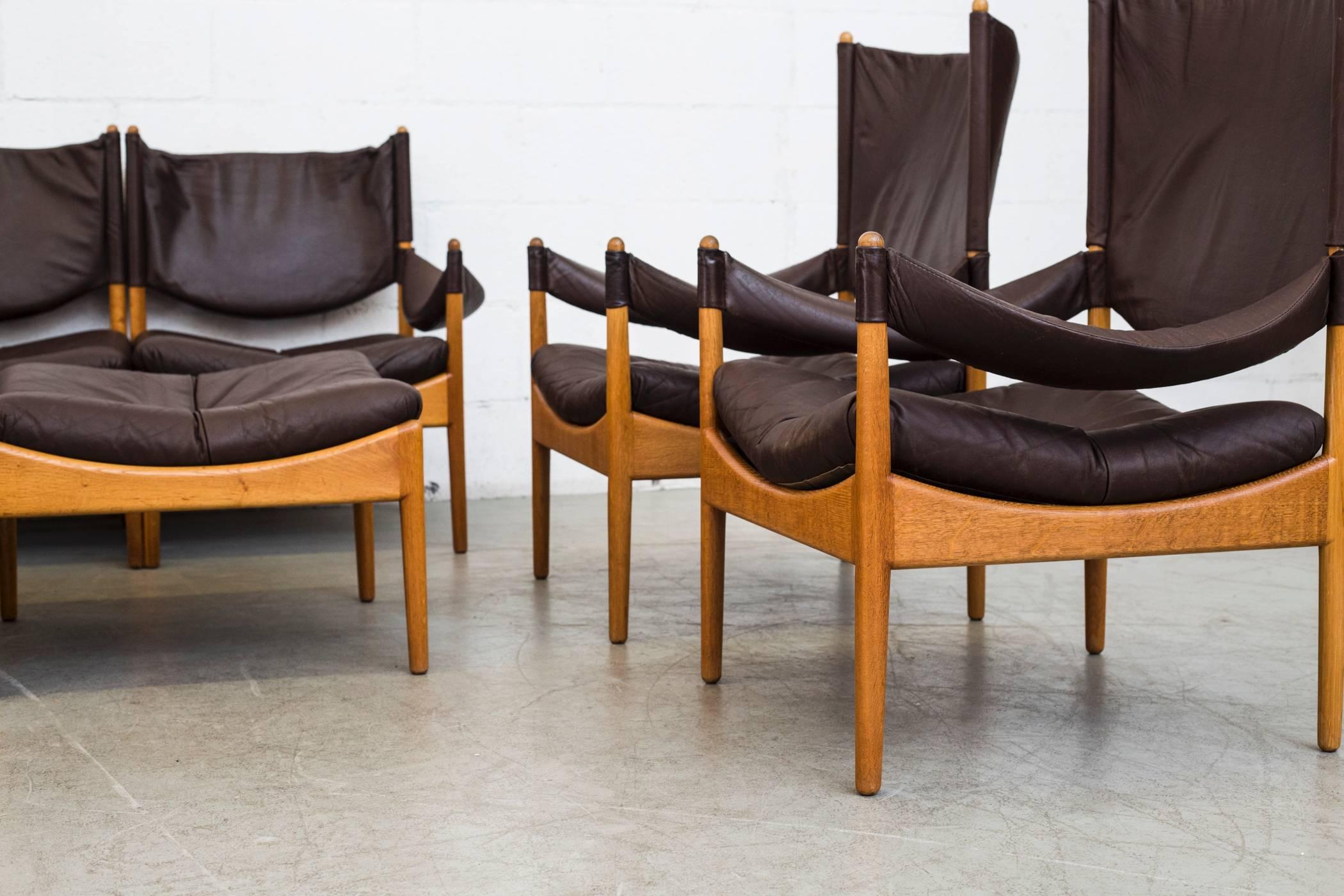Nine element lounge suite designed by Kristian Vedel in 1960. Chocolate leather and oak frames. Set consists of two tall lounge armchairs, one short armchair, two single armchairs and one armless with two ottomans and a side table with reversible