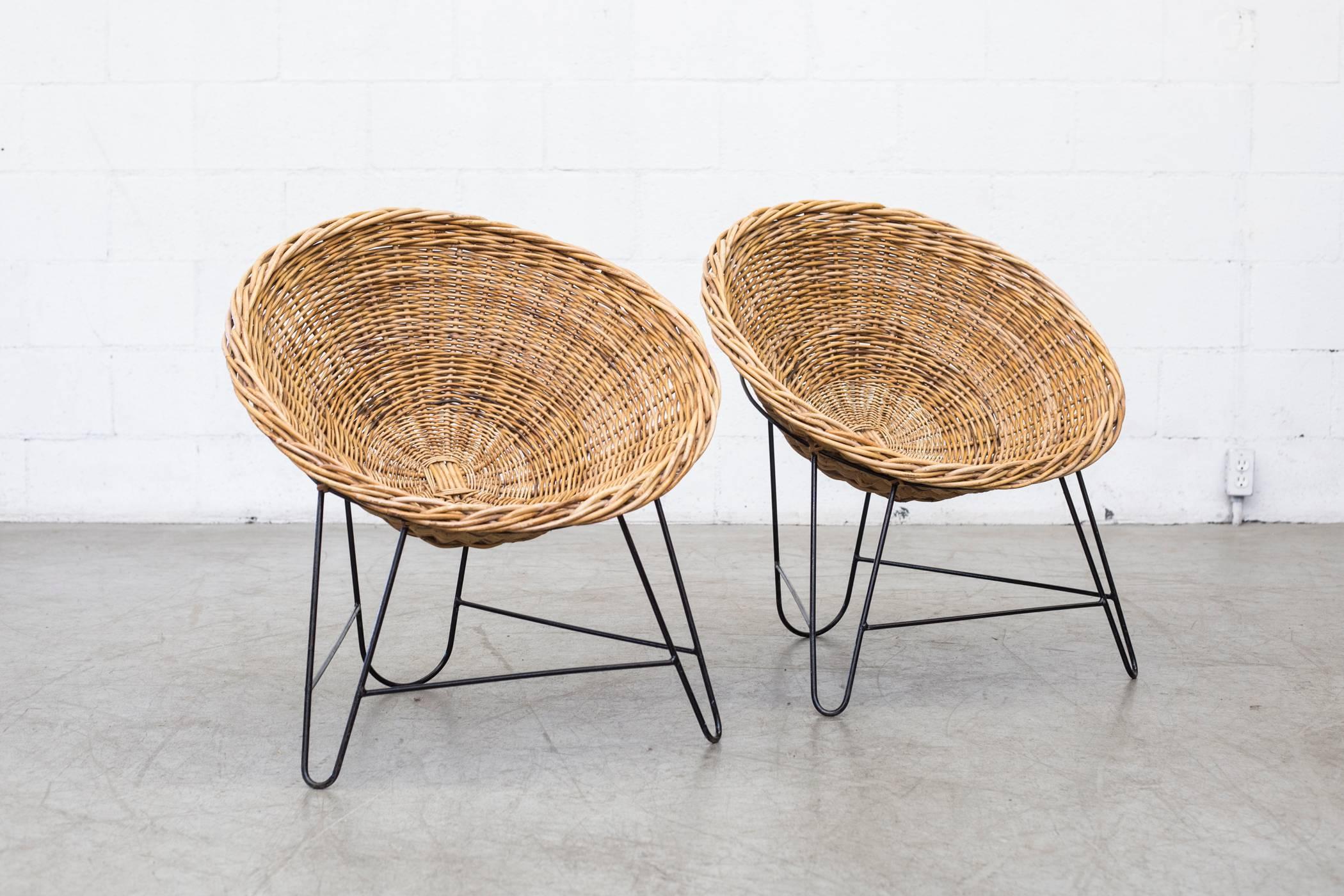 Light woven rattan basket chairs with black enameled metal frame. In original condition with visible signs of wear. Rattan and frame colors vary from chair to chair and may differ from the ones photographed Price per item.
