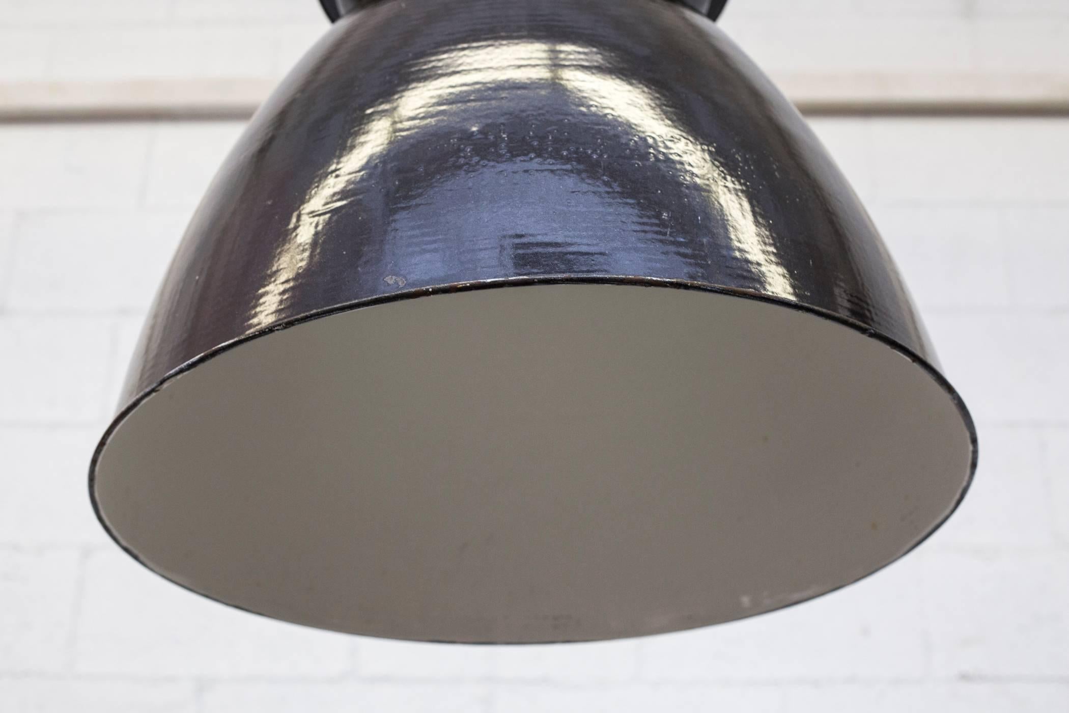 Gorgeous Industrial enameled factory ceiling lamp with black enameled exterior and white enameled interior. All in original condition with visible wear and minimal chipping consistent with age and usage. Other similar lamps in other color tones