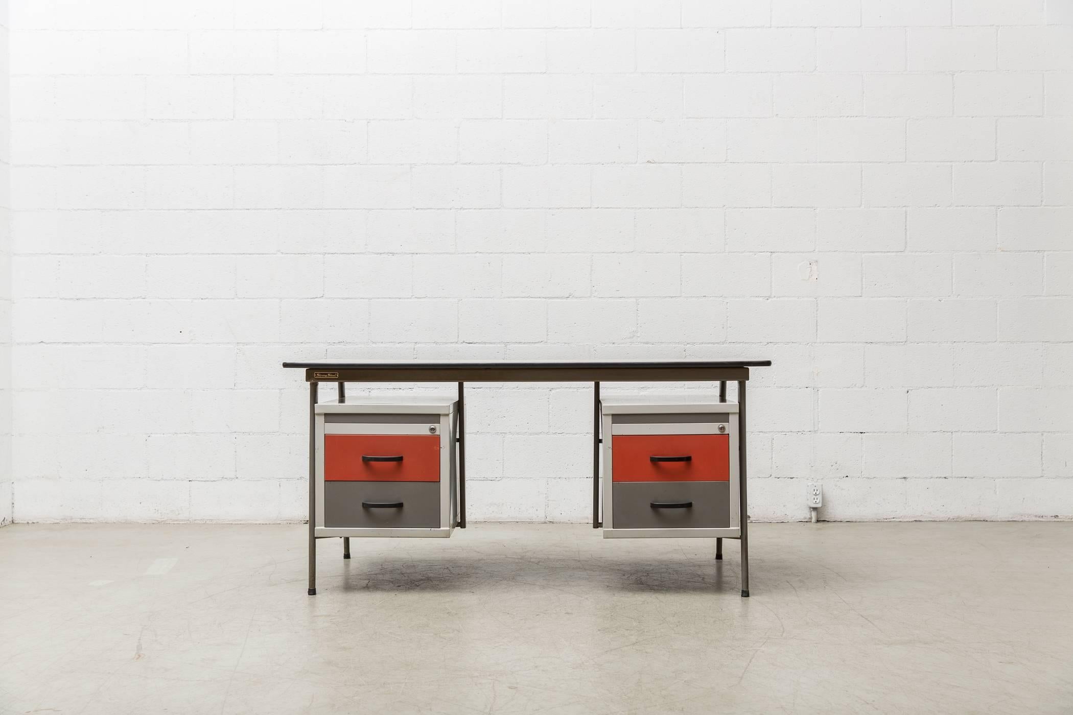 Stunning 1950s Drentea office desk with light grey enameled metal frame, red and grey enameled metal drawers with linoleum top. Tag Reads 'Strong Steel.' In original condition with wear consistent with its age and usage. Chairs opening is 19.75