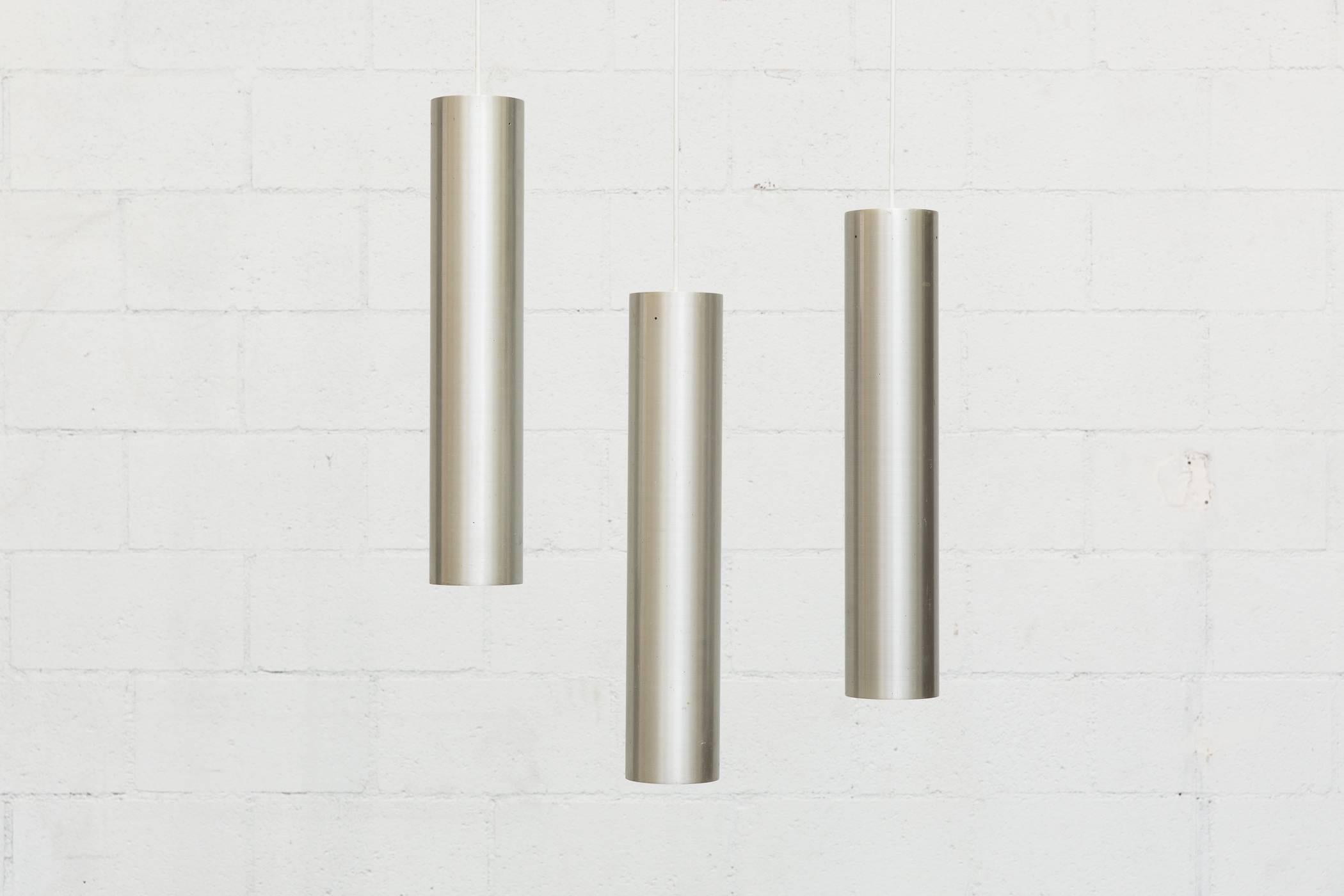 1960s Mid-Century set of three elongated brushed aluminum tubular pendants. Manufactured by renowned Dutch lighting company Raak Lichtarchitectuur out of Amsterdam. Founded in 1954 by Carel O. Lockhorn (who originally worked for Philips) the