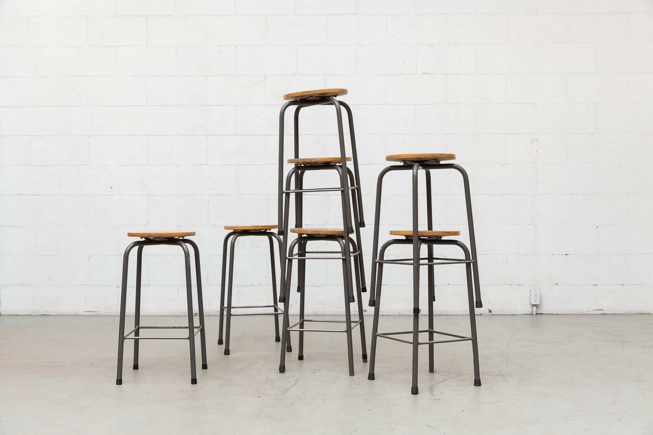 Nice stock of Industrial task stools with grey enameled metal frames and wood seats. Some drilled, carved, loved. Very original condition.