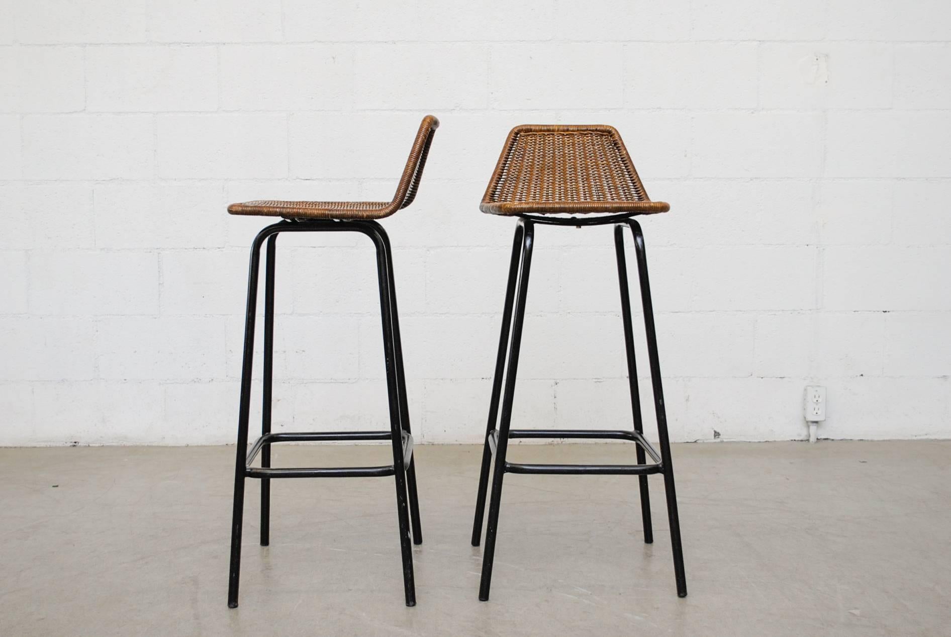 Pair of Dirk van Sliedregt tall angle backed rattan bar seat with black enameled tubular frame. Dark patina to seating, in original condition with visible signs of wear, minimal wicker and enamel loss. Set price.