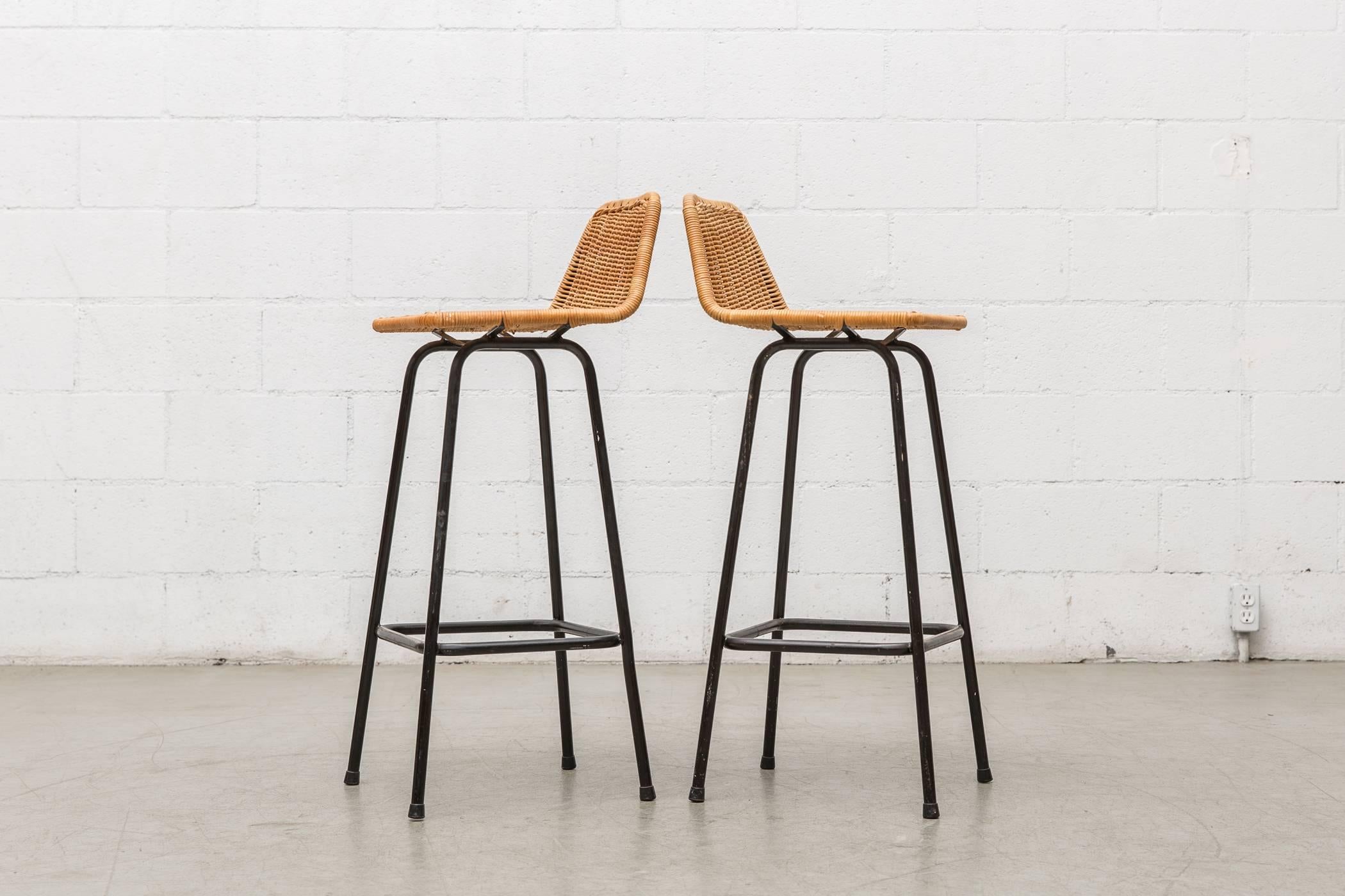 Pair of Dirk van Sliedregt tall angle backed rattan bar stools with black enameled tubular frame. Light patina to seating, in original condition with visible signs of wear, minimal wicker and enamel loss. Other sizes and variations available and