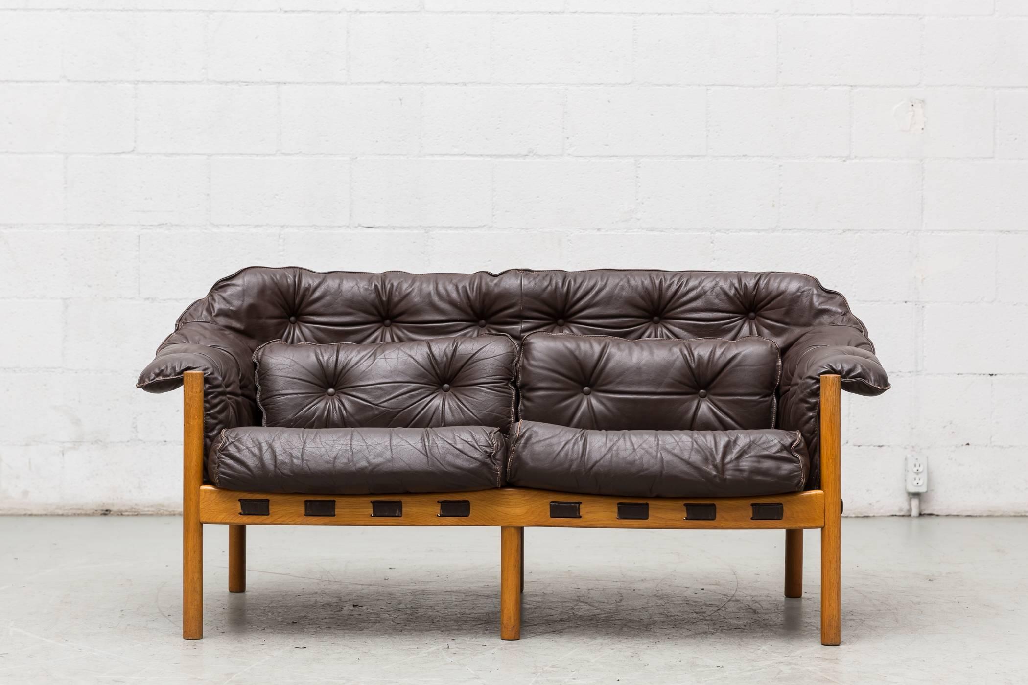 Sweet little Arne Norell style love seat with chocolate brown leather tufted cushions in original condition. Visible signs of wear, some of the lining is worn through behind the leather. Frame in good original condition.