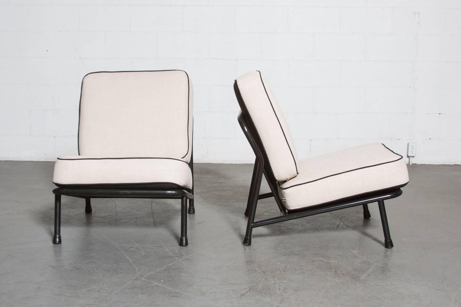 Pair of black enameled metal tubular framed easy chairs with new upholstered cushions. These chairs sit low to the ground and can be used as a two-seat sofa, or two individual easy chairs. By Swedish Designer Alf Svensson for Wagemans & Van Tuinen