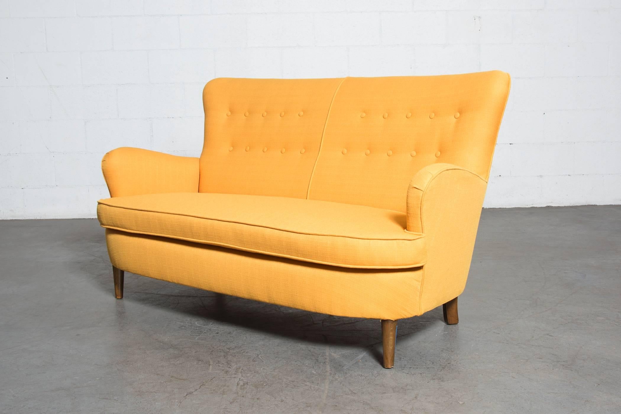 Fab sunshine yellow upholstered wingback sofa, great button detail, sweeping lines. Frame is in original condition with some wear to feet consistent with age and use.