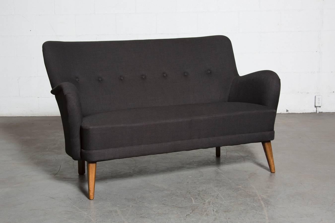 Theo Ruth loveseat by Artifort in newly upholstered charcoal black fabric. Frame is original, feet show signs of wear consistent with age and use.

Theo Ruth was an interior and furniture designer whose most famous design was his 1952 Congo chair